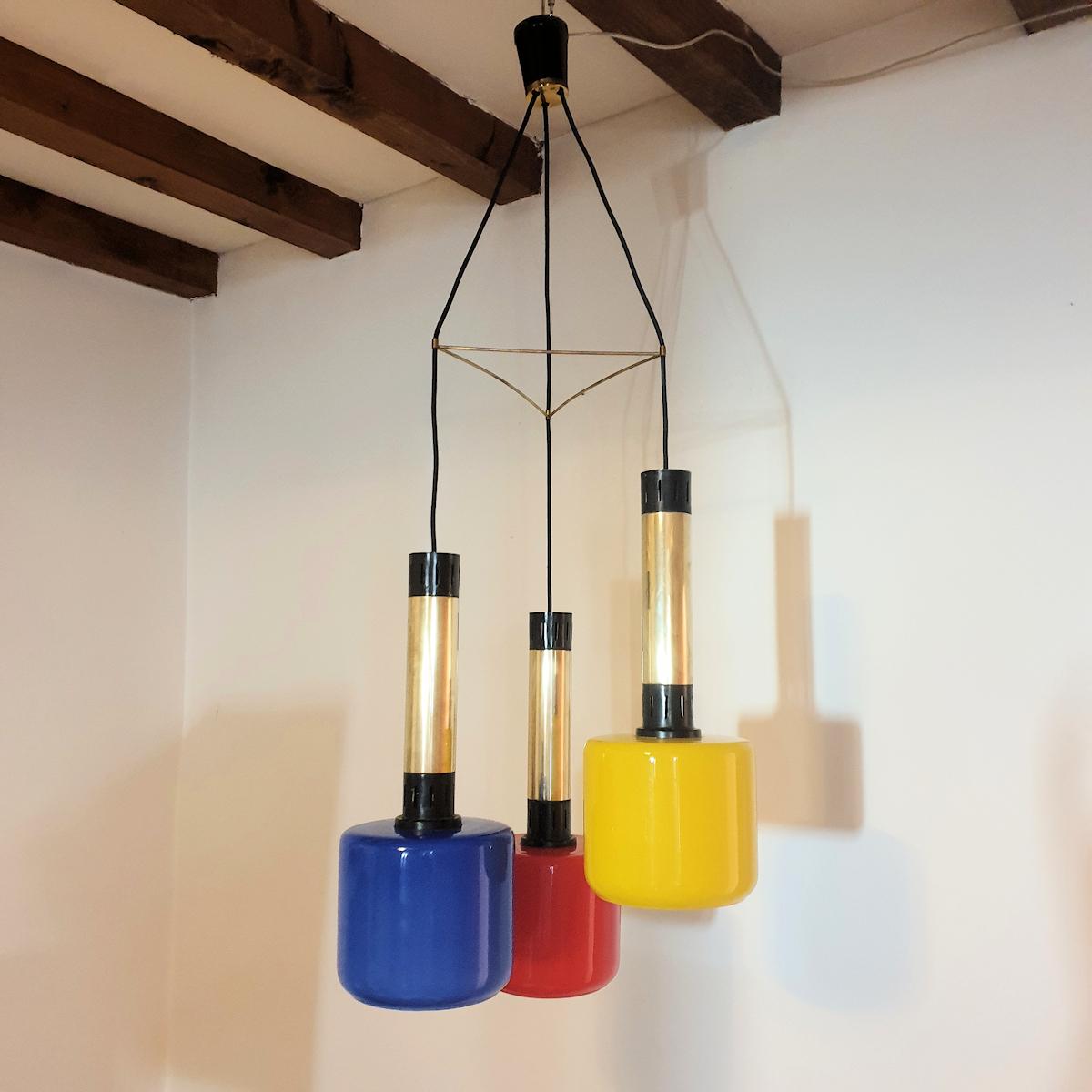 Glass and brass pendant chandelier, by Stilnovo, Italy 1960s.
Three primary colors glass shades for this original Italian vintage chandelier.
A famous Stilnovo design from the Mid Century, trendy and modern.
The vintage chandelier is made of three