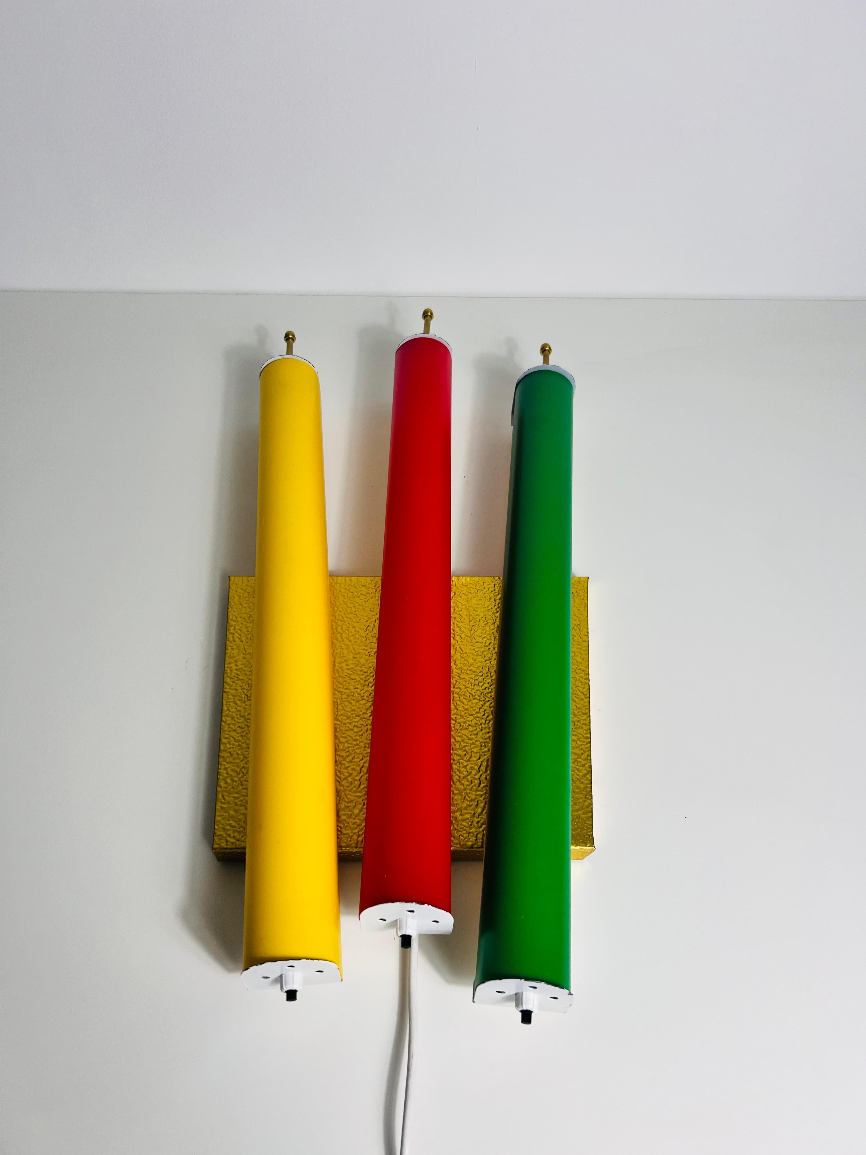 Esta lámpara de pared Century Modern de los años 60, excepcionalmente rara, es una auténtica obra maestra italiana. Con tres luces LED de colores sobre un fondo cuadrado de latón, esta lámpara emana el vibrante estilo de diseño de los años 50 y 60.