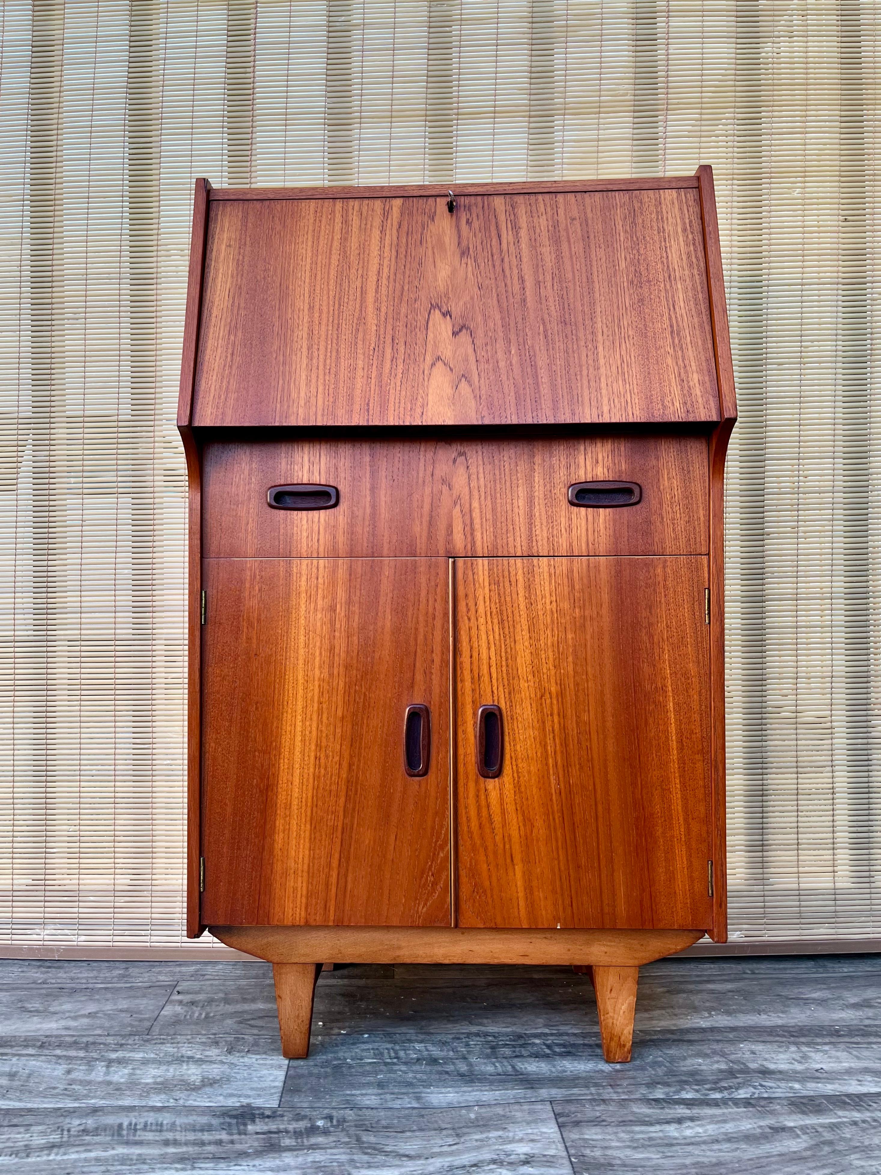 Vintage Mid Century Modern Compact Drop Down Secretary Desk . Circa 1960s
Features a sleek Mid Century Modern Design, the perfect compact size to fit in any small area or room, a drop down writing surface with the original key, a drawer, and a