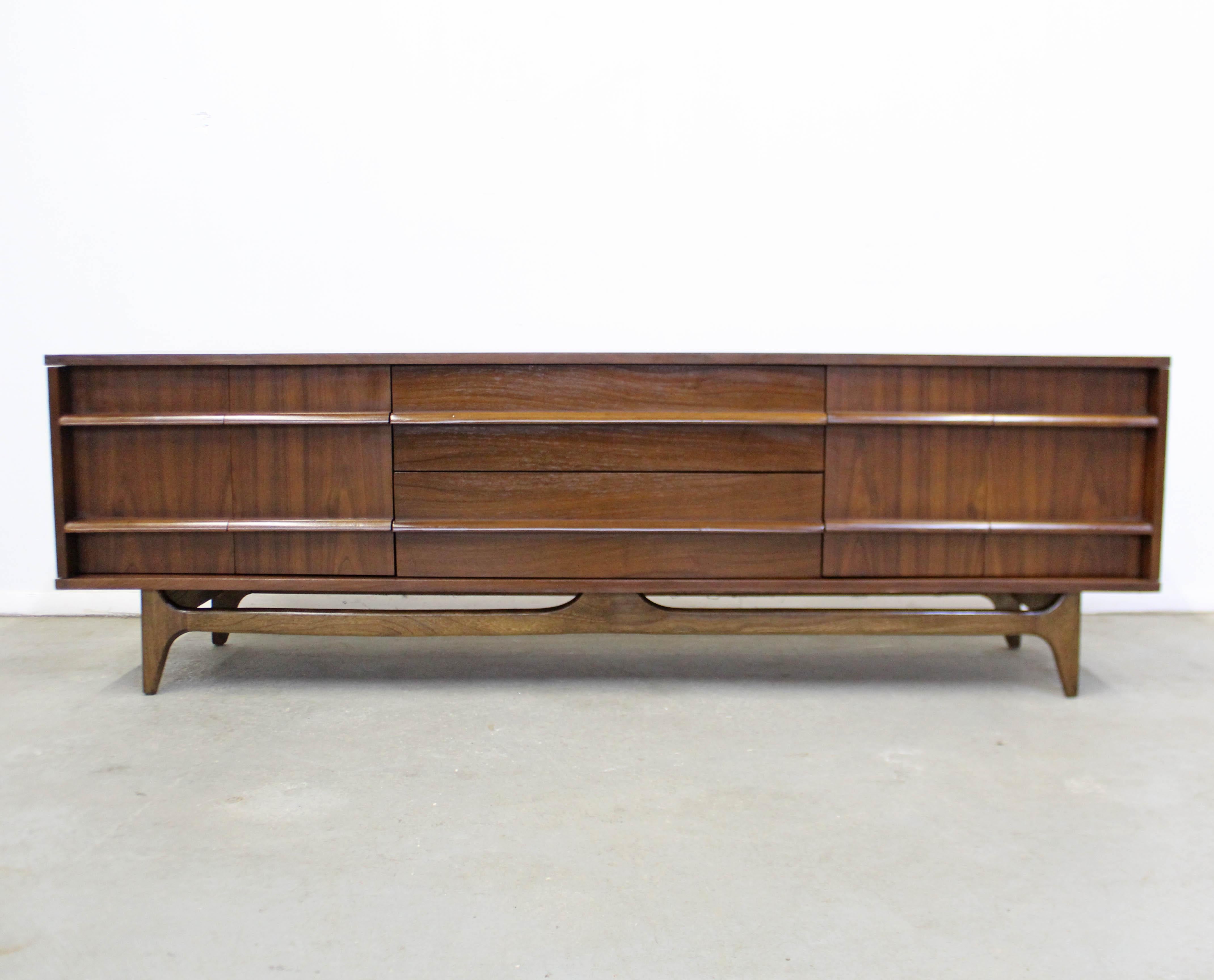 Offered is a vintage Mid-Century Modern concave front credenza with sculpted pulls made by Young Manufacturing. Features a concave front with two center drawers, bi-folding doors on the sides with inner storage. It is in overall good condition, has