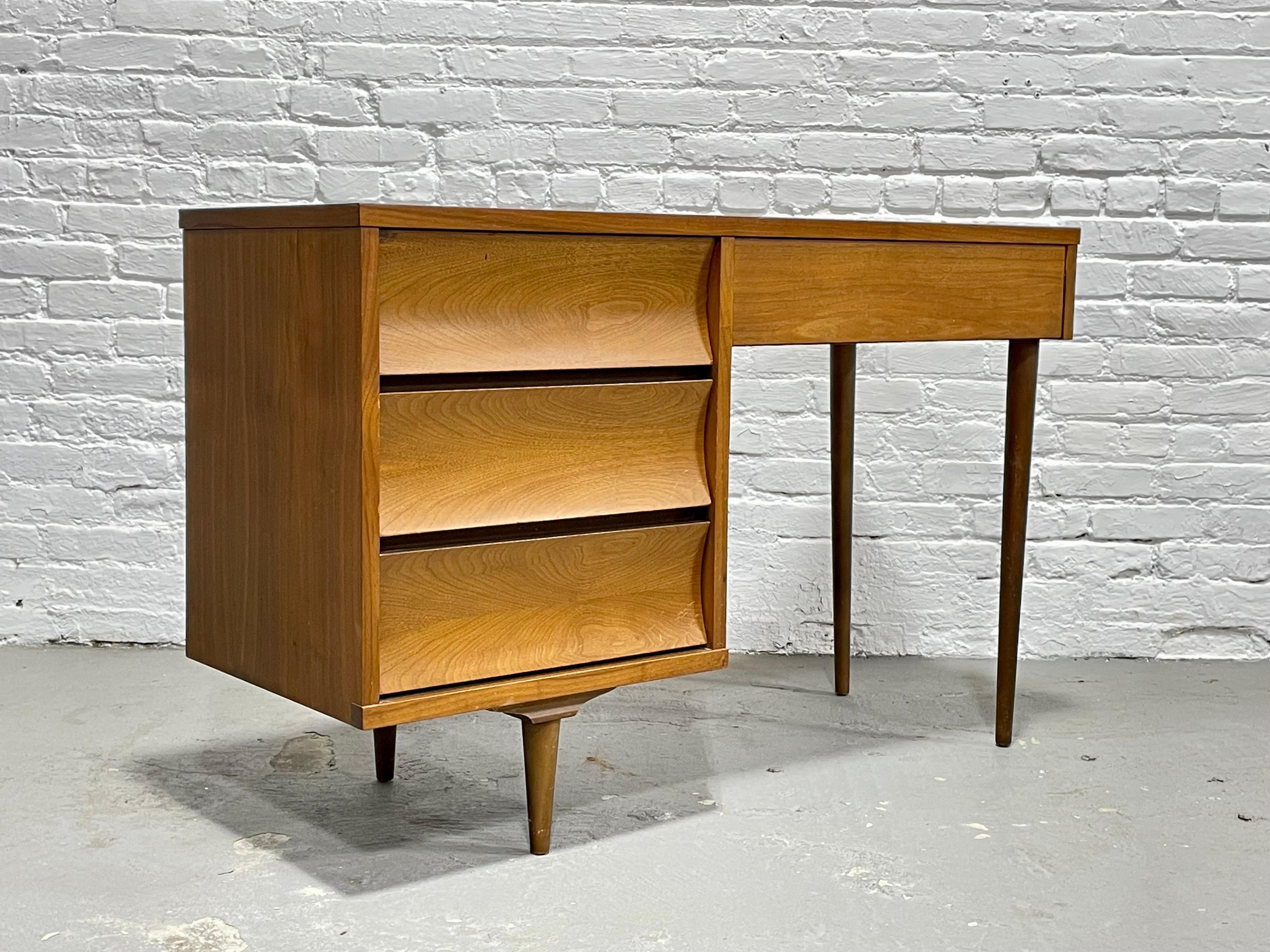 Mid Century Modern Walnut Desk by Johnson Carper, featuring concave drawers and four spacious drawers for plenty of storage space. The tabletop is a laminate (formica) woodgrain, perfect for withstanding the wear and tear of a work surface. This
