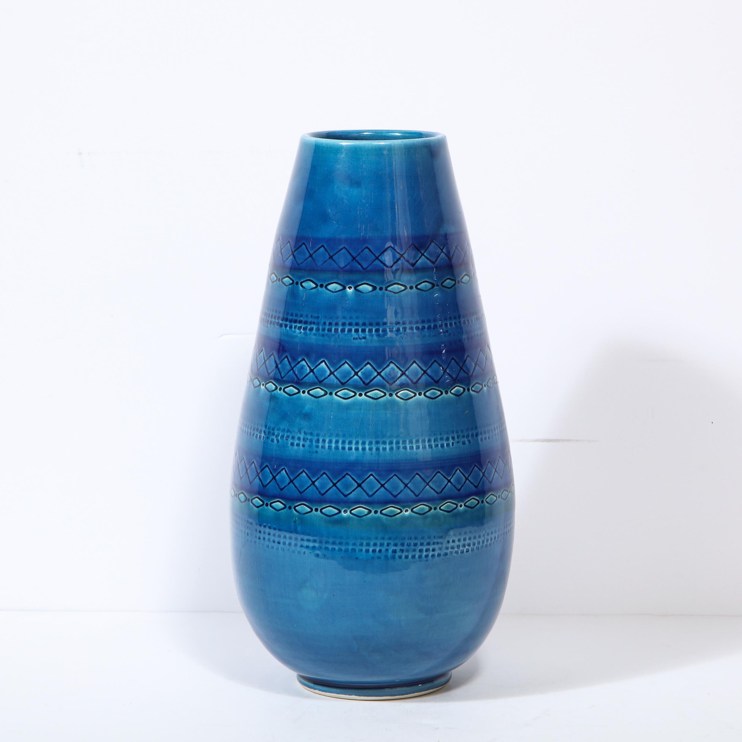 This refined Mid-Century Modern vase was realized in Italy, circa 1960. It offers a conical azure blue body with banded geometric detailing running horizontally across its surface. With its vibrant and sophisticated color, and clean modernist lines,