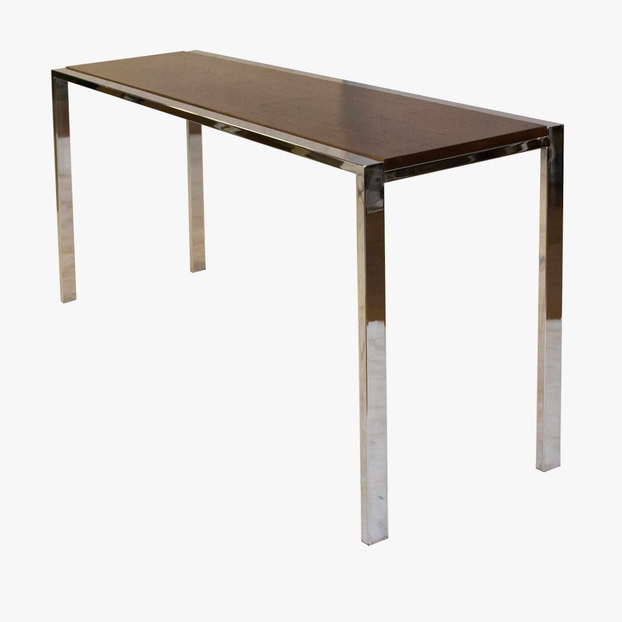 Beautiful small console table. Perfect for an entryway or behind a low sofa. Elegant and delicate chrome legs surround the walnut veneer top. The connection runs the length for the table, allowing the chrome to contrast with the walnut. Two welded