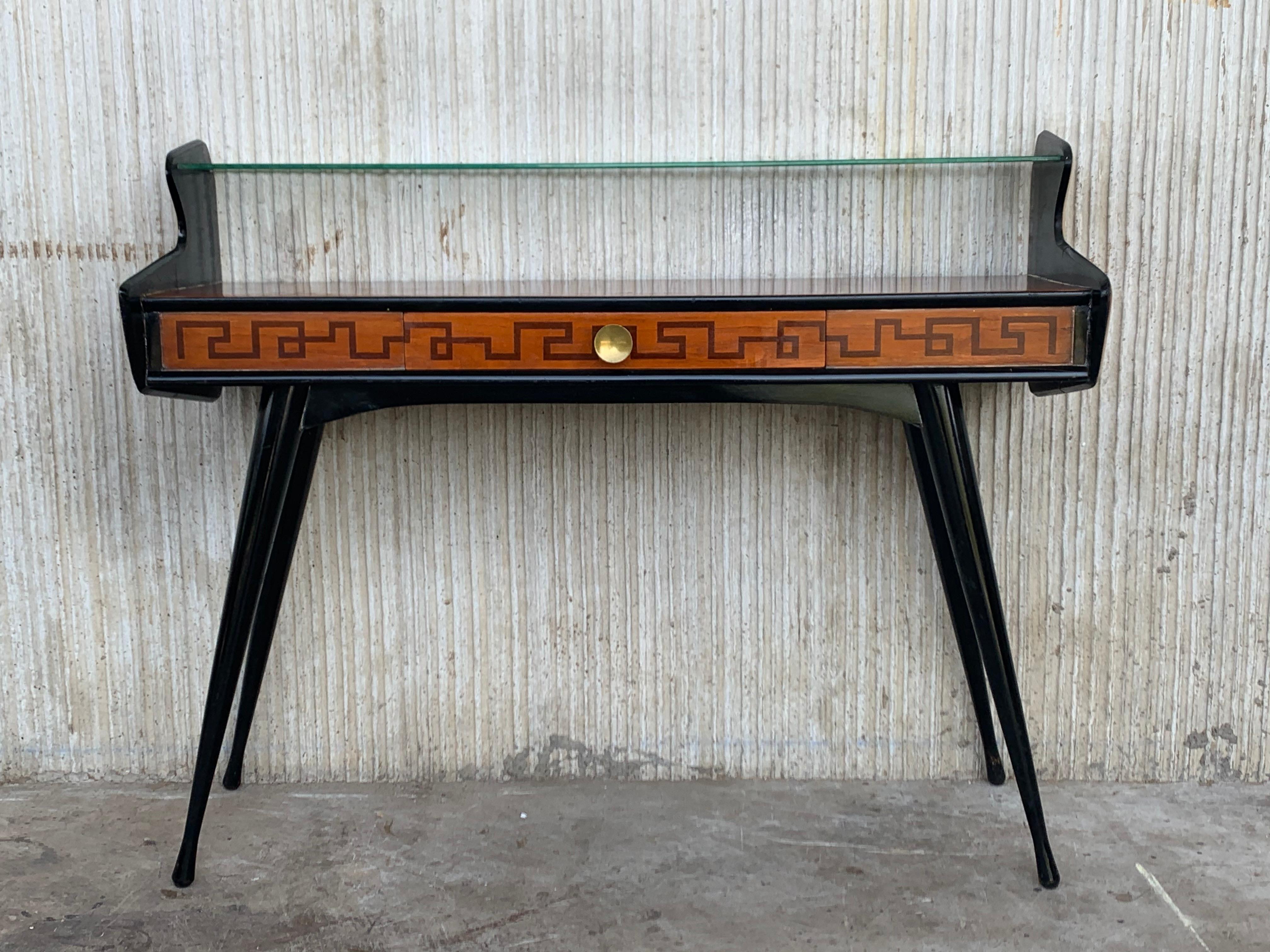 Very elegant and refined Italian 1950s Mid-Century Modern, in typical Art Deco design and shape, console table with teak wood, ebonite and double sides, with second glass top . This piece comprises of flared spider legs. This console makes a great