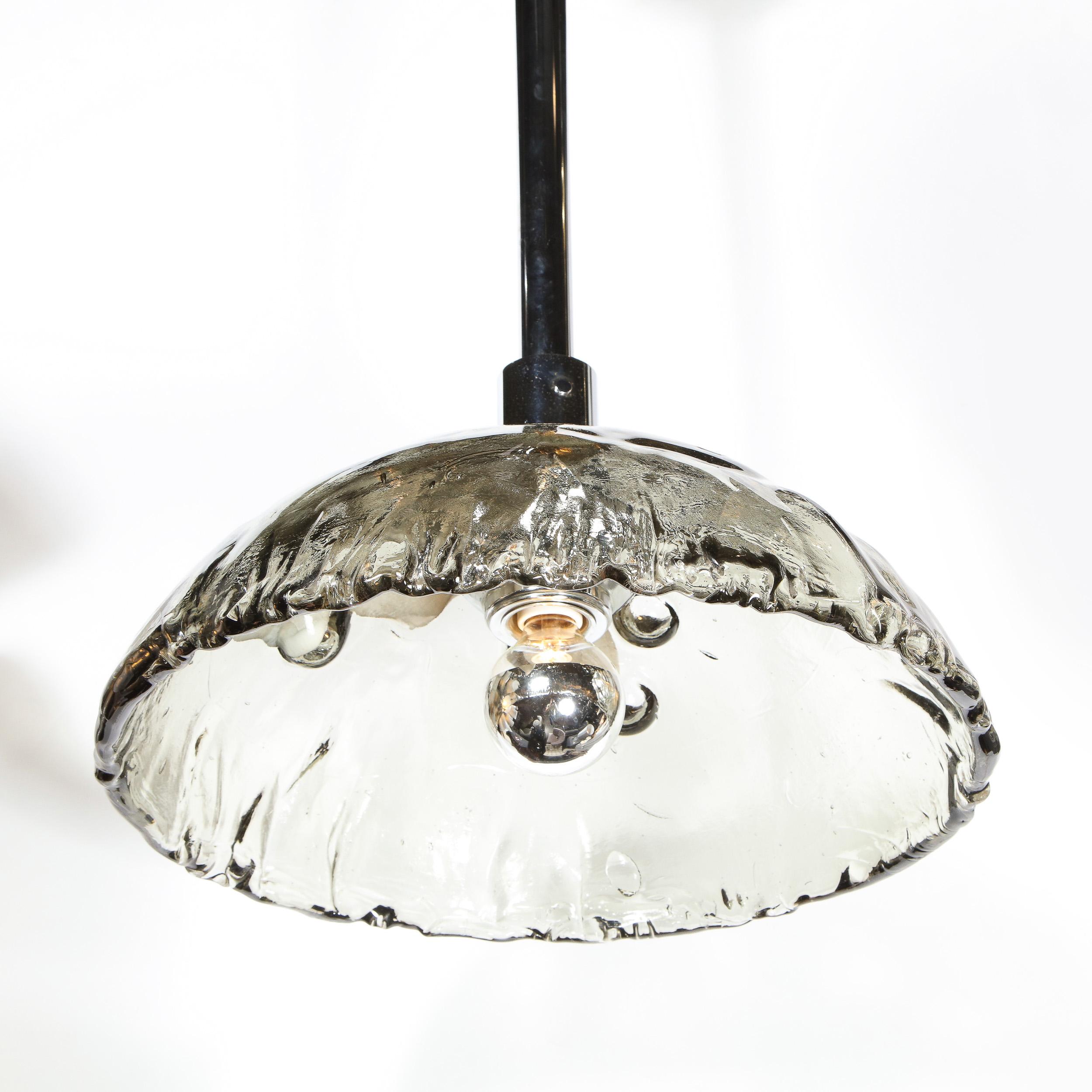 This elegant Mid-Century Modern chandelier was realized in Murano, Italy- the island off the coast of Venice renowned for centuries for its superlative glass production- by the storied atelier of Mazzega, circa 1970. The chandelier features a convex
