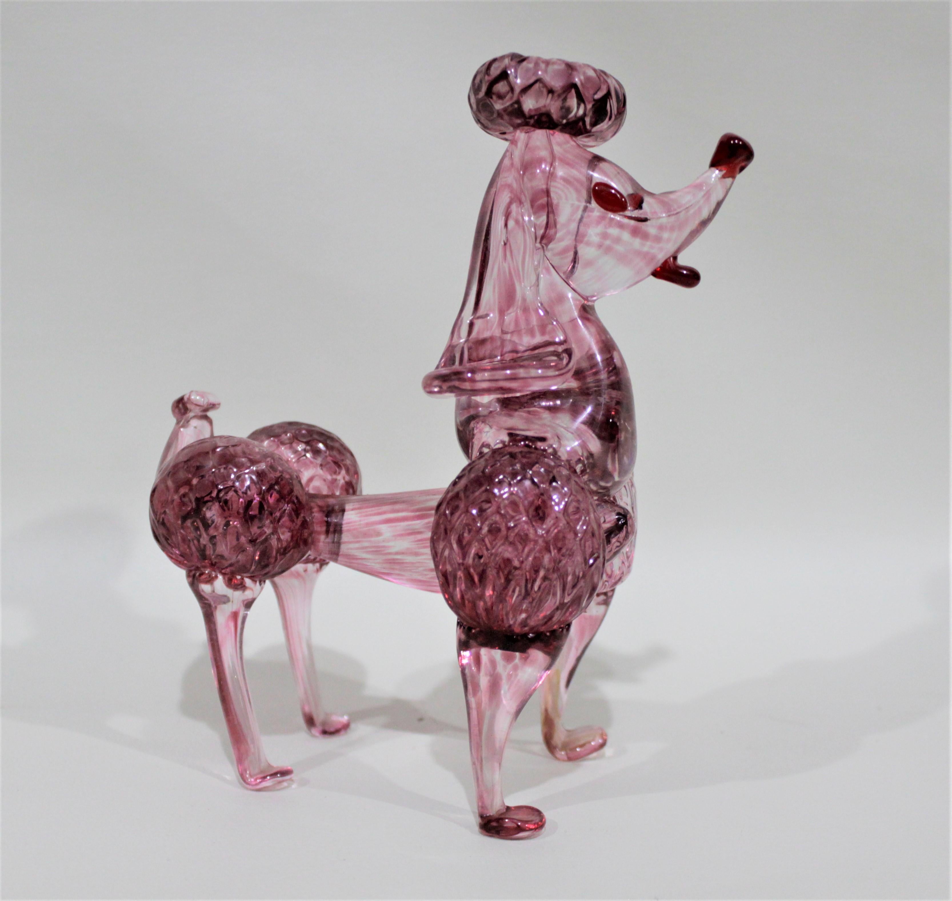 This solid pink or cranberry art glass stylized poodle figurine is unmarked, so its origins cannot be determined, but was most likely made in Italy in the Mid-Century Modern period and style. The figurine is done with a mixture of clear and