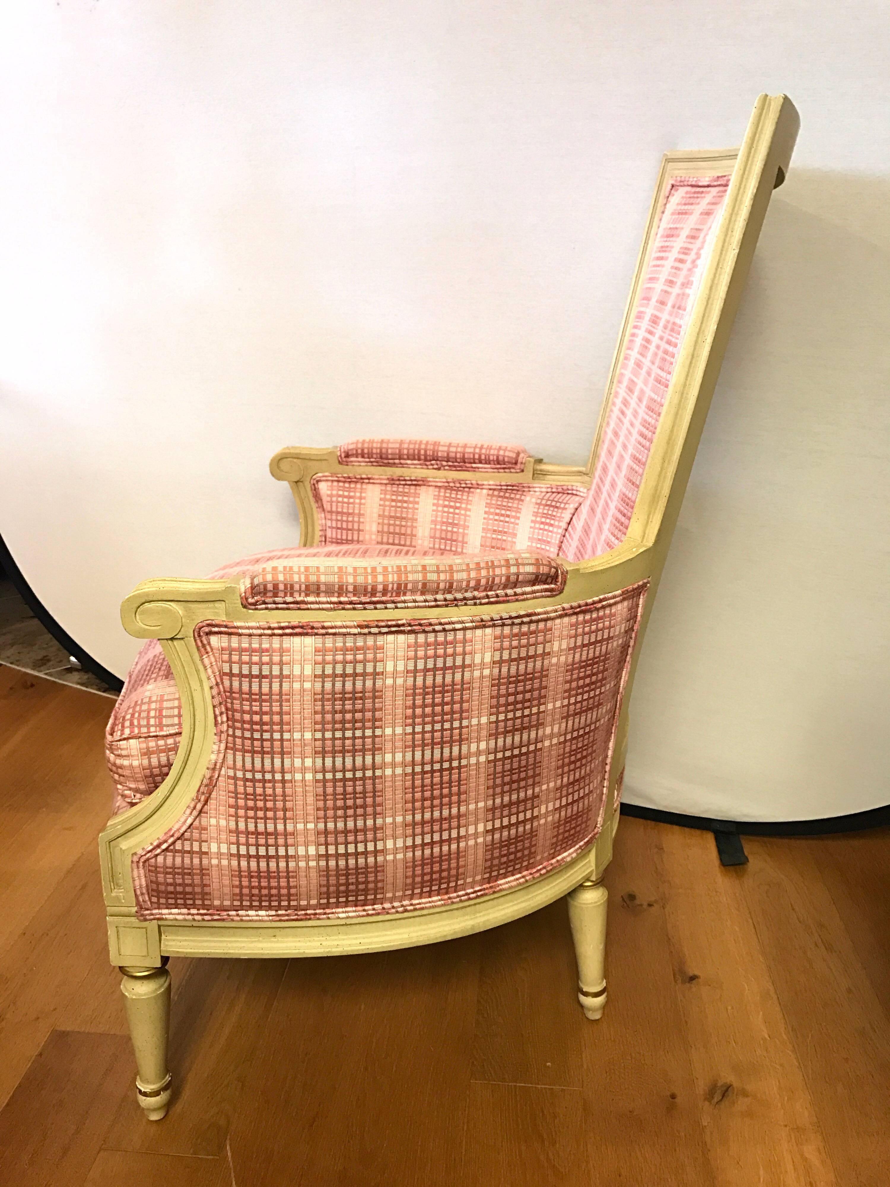 Curvaceous yet comfortable cream painted armchairs newly upholstered in a silk blend pink plaid fabric trimmed with double welting. Down cushions.