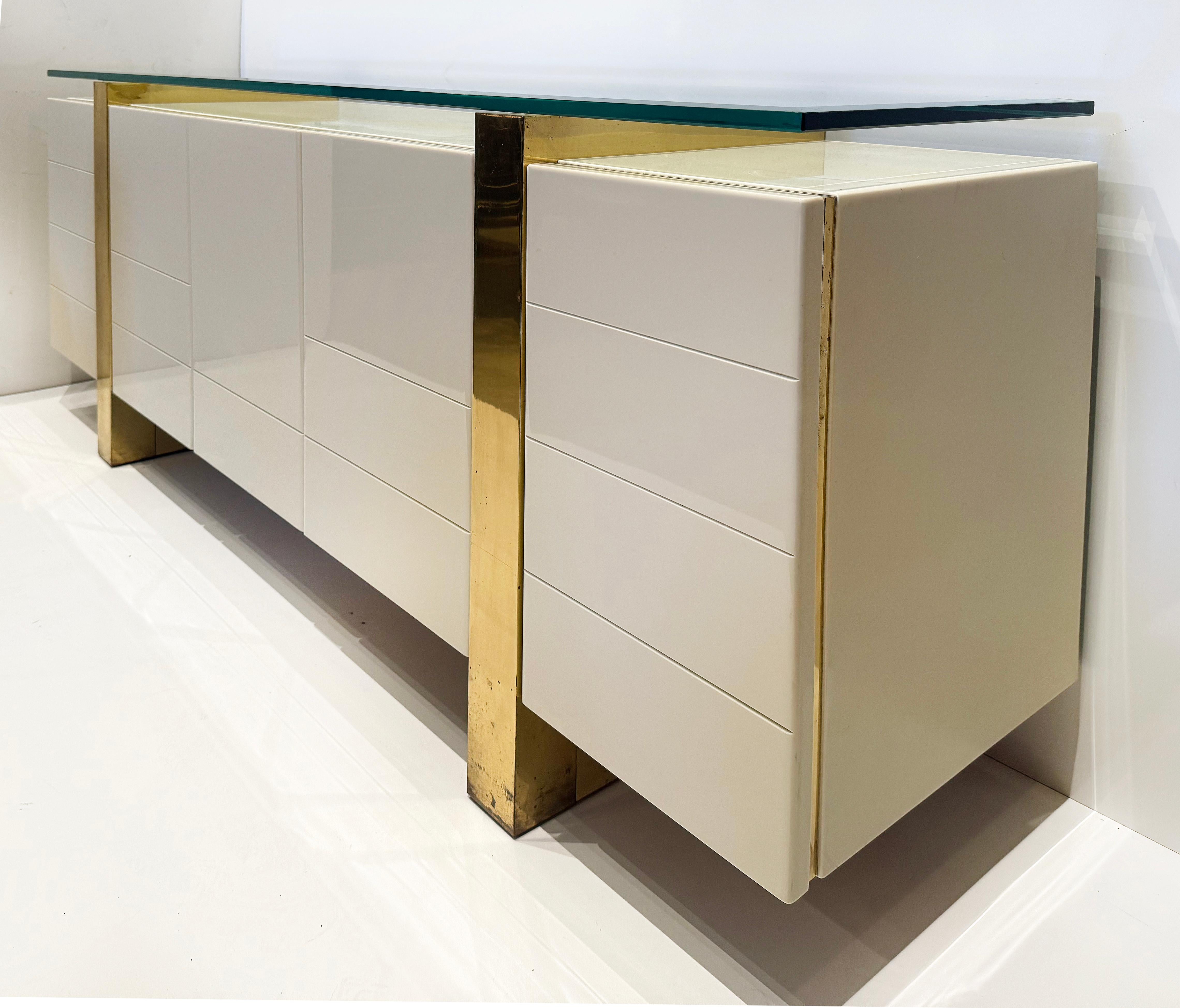 Credenza moderna di metà secolo, ottone e vetro, ispirata a Cardin

In vendita c'è una credenza moderna di metà secolo con legno laccato e accenti in ottone. Il  Le colonne centrate in ottone si innalzano per sostenere un piano in vetro spesso che