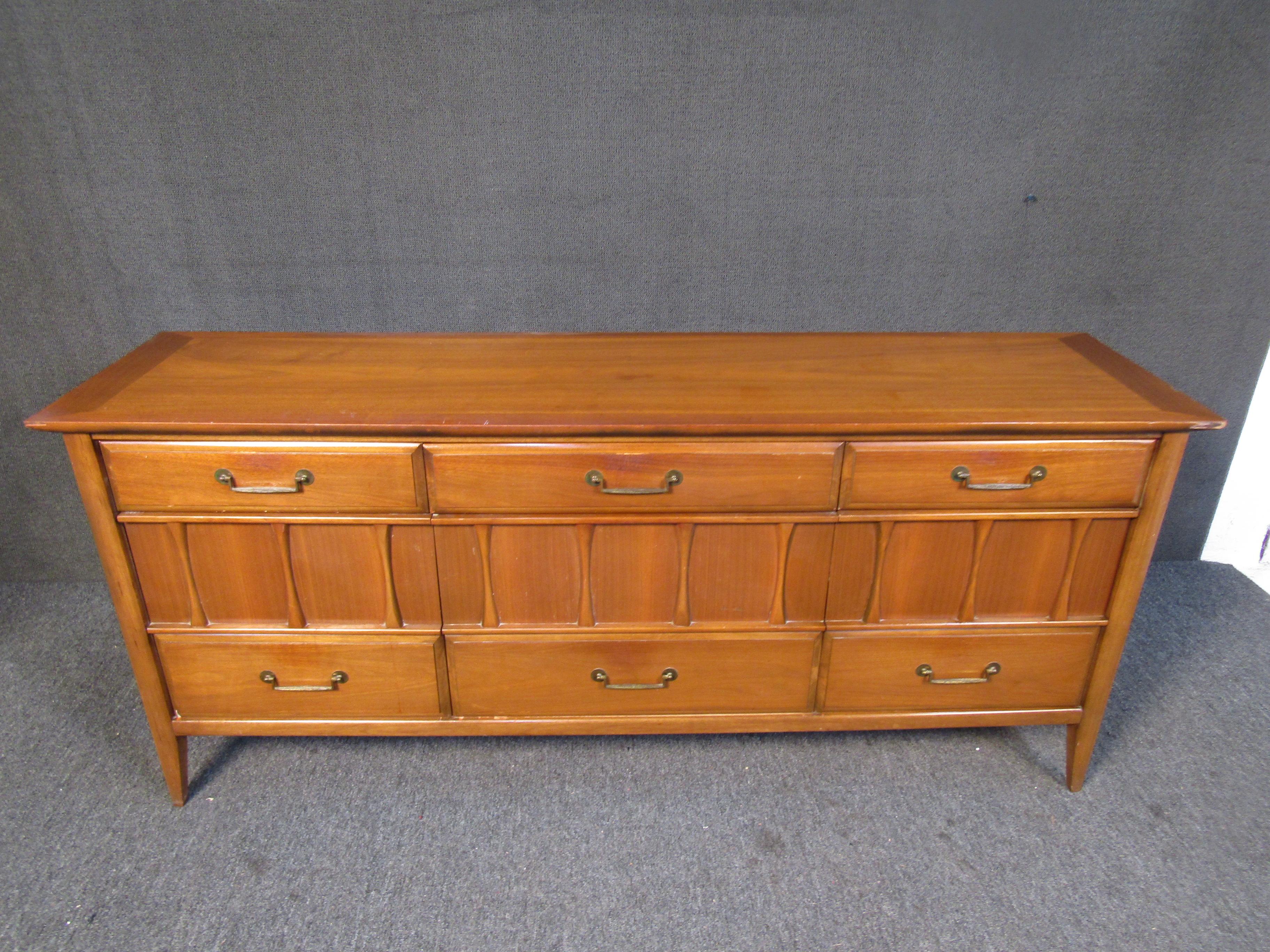 This vintage credenza by Kroehler combines walnut wood with metal drawer pulls and sculpted accents. Mid-Century quality makes this piece a great investment for any space. Please confirm item location with seller (NY/NJ).