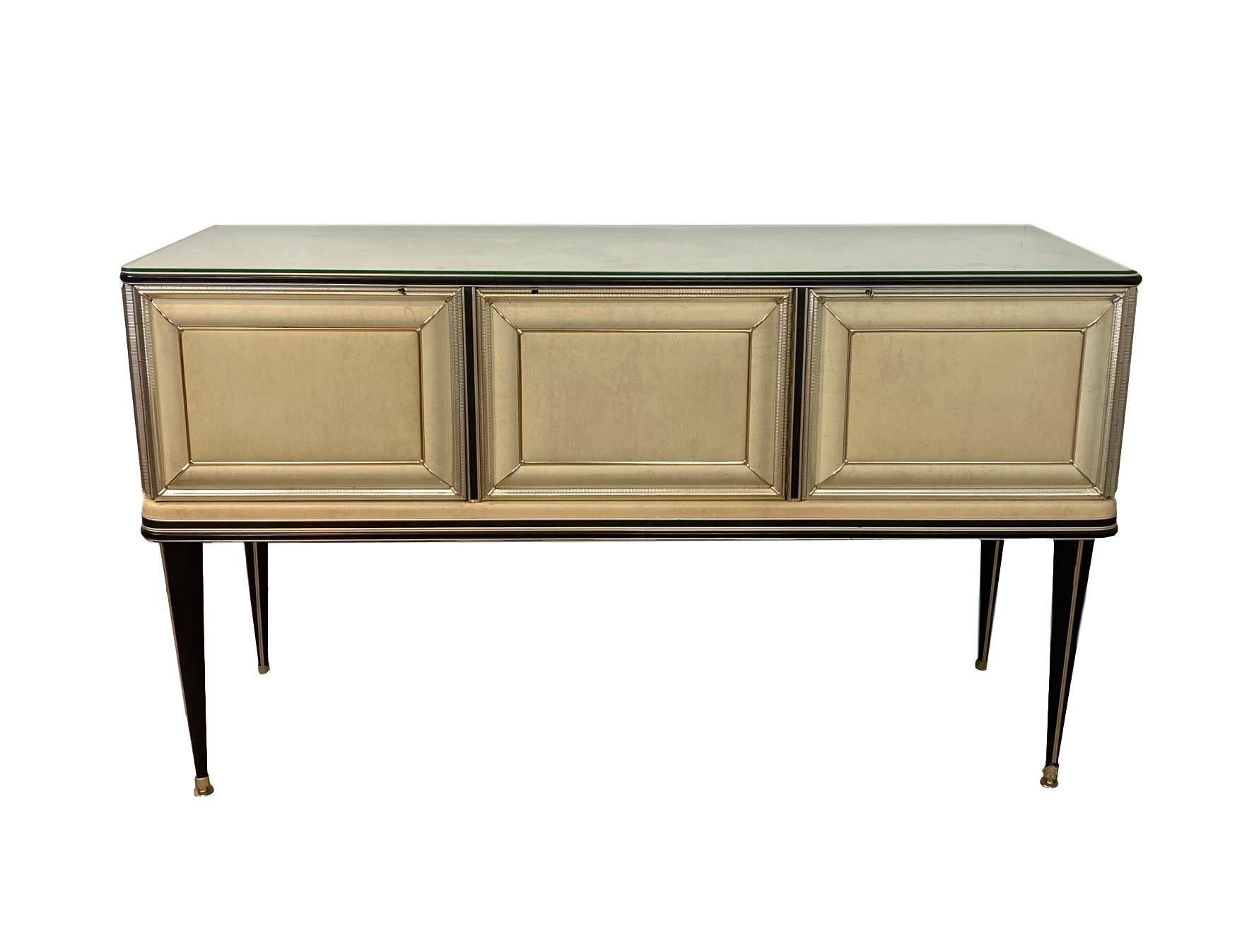 Mid-Century Modern credenza by Umberto Mascagni, Italian, circa 1950. Covered in cream and black faux leather; banded, mounted, and molded with Anodized Aluminum.
With signature badge: 'UMBERTO MASCANI, BOLOGNA.'
Umberto Mascagni founded Mascagni