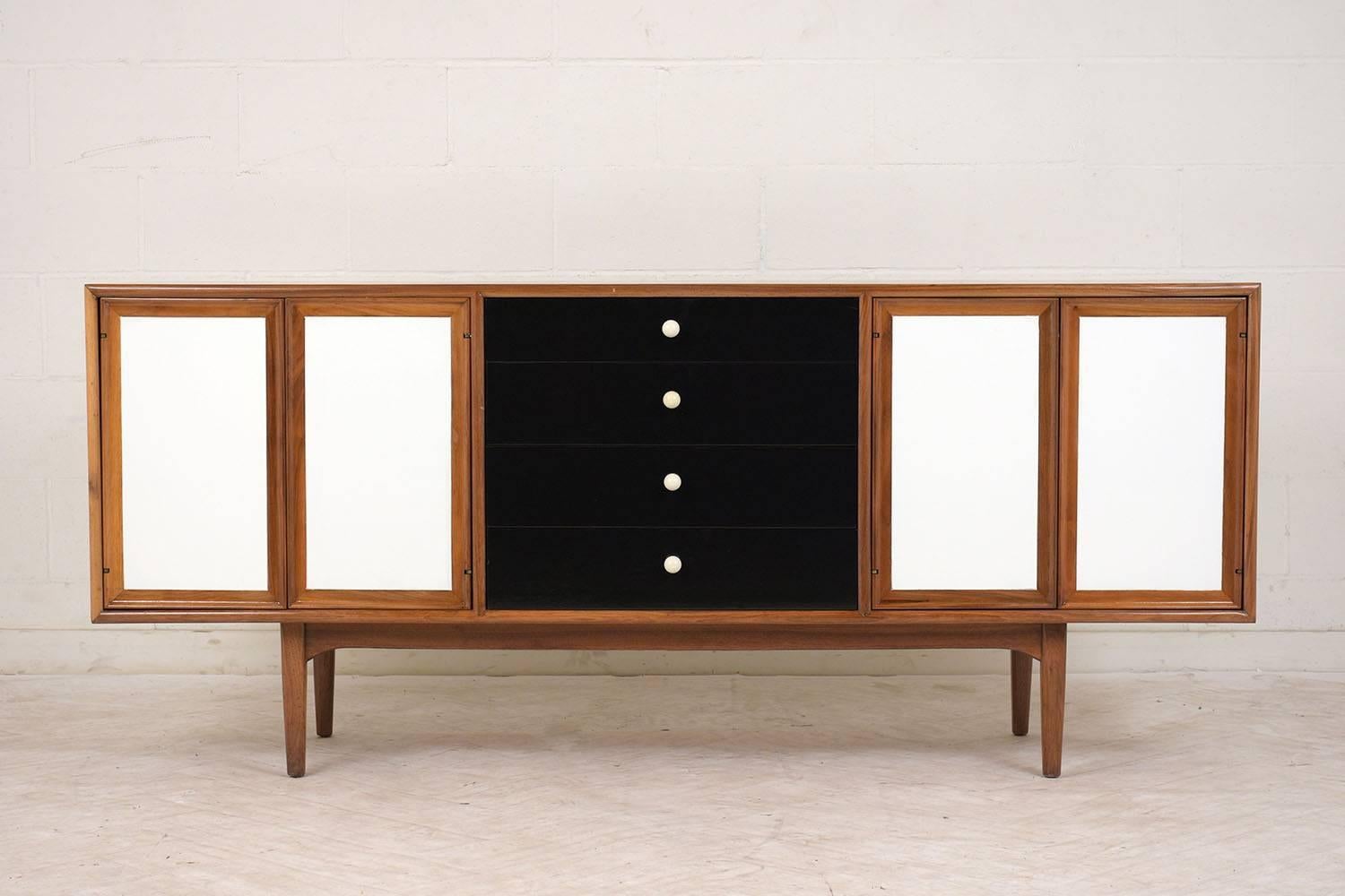 This 1960s Mid-Century Modern credenza is made by Drexel Declaration and has been completely restored. The walnut wood credenza is finished in a rich walnut color with a lacquered finish. There are for cabinet doors that are painted a bright white