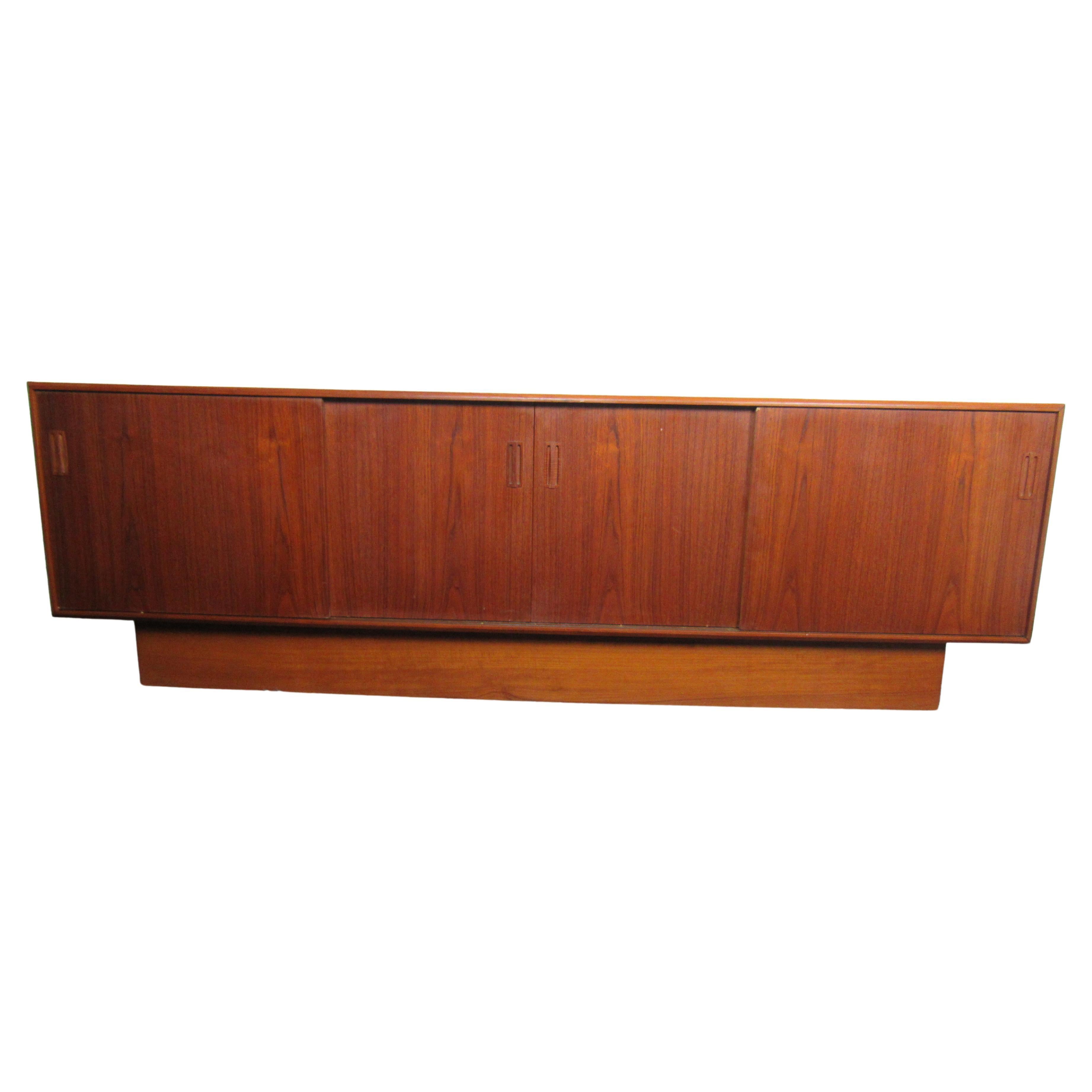 Radiant teak wood grain and an understated design make this vintage credenza an elegant addition to any interior. Sliding doors reveal spacious shelving for organization. Please confirm item location with seller (NY/NJ).