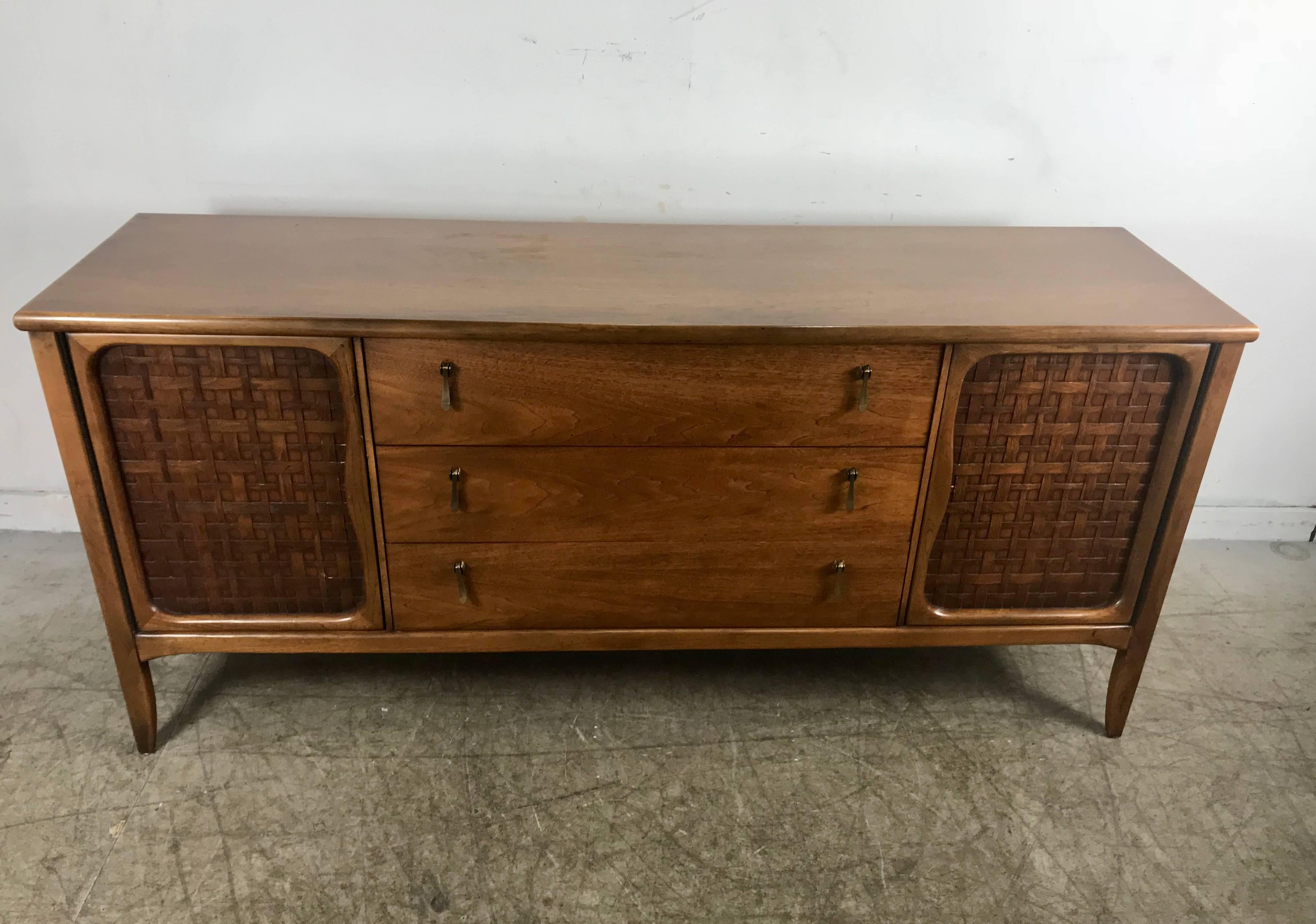 Mid-Century Modern credenza or sideboard by Lane Perception. Classic Modern design. featuring three generous drawers and two doors. Stunning walnut finish. Superior quality and construction. Baslet weave door fronts. Stylized drop brass pulls.