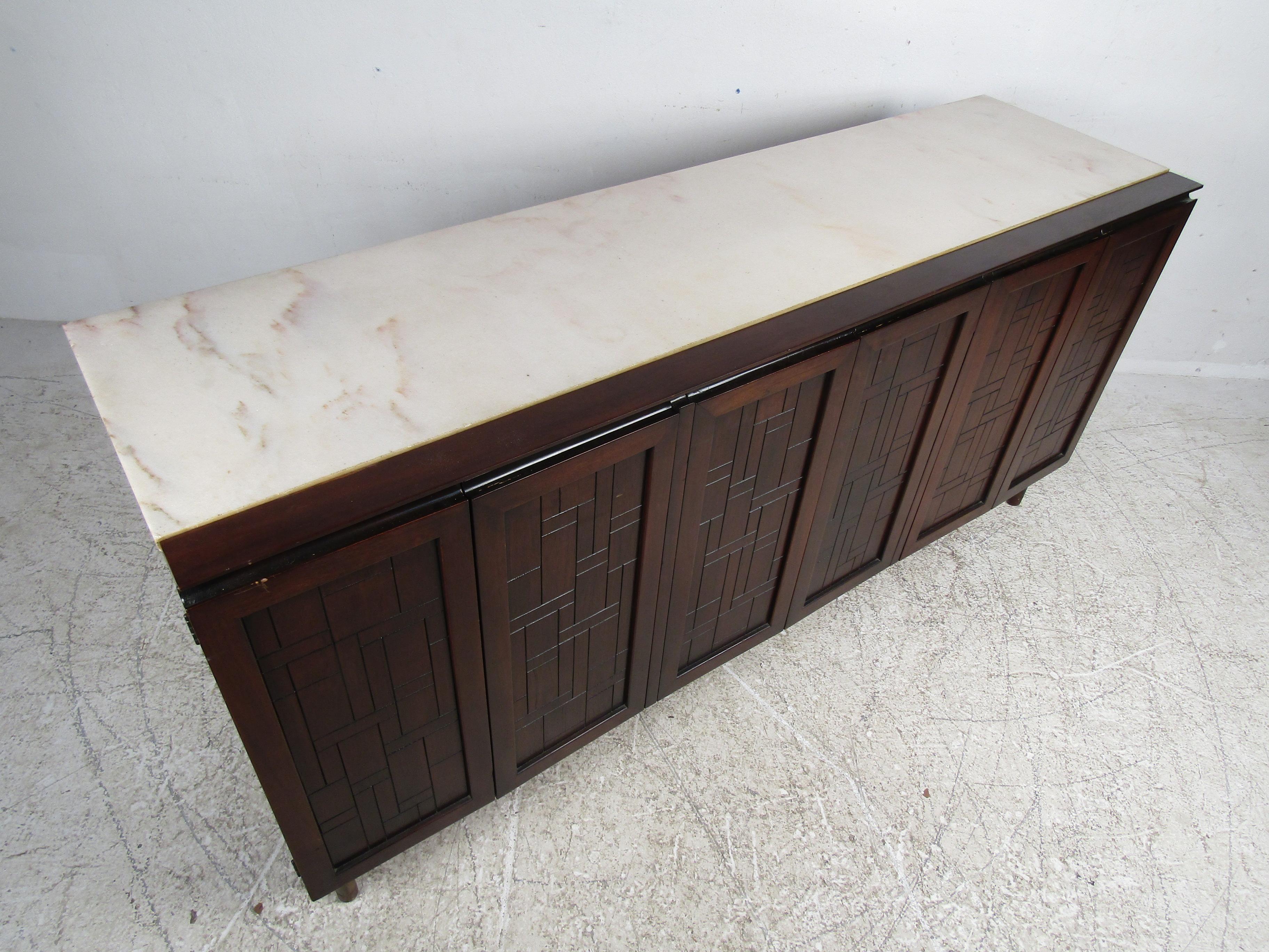 Impressive midcentury credenza from John Stuart, designed by Bert England. A handsome piece with brutalist style panels lining the cabinet fronts. Hinged cabinet doors open to reveal drawers with dovetail joinery and sculpted pulls, along with a