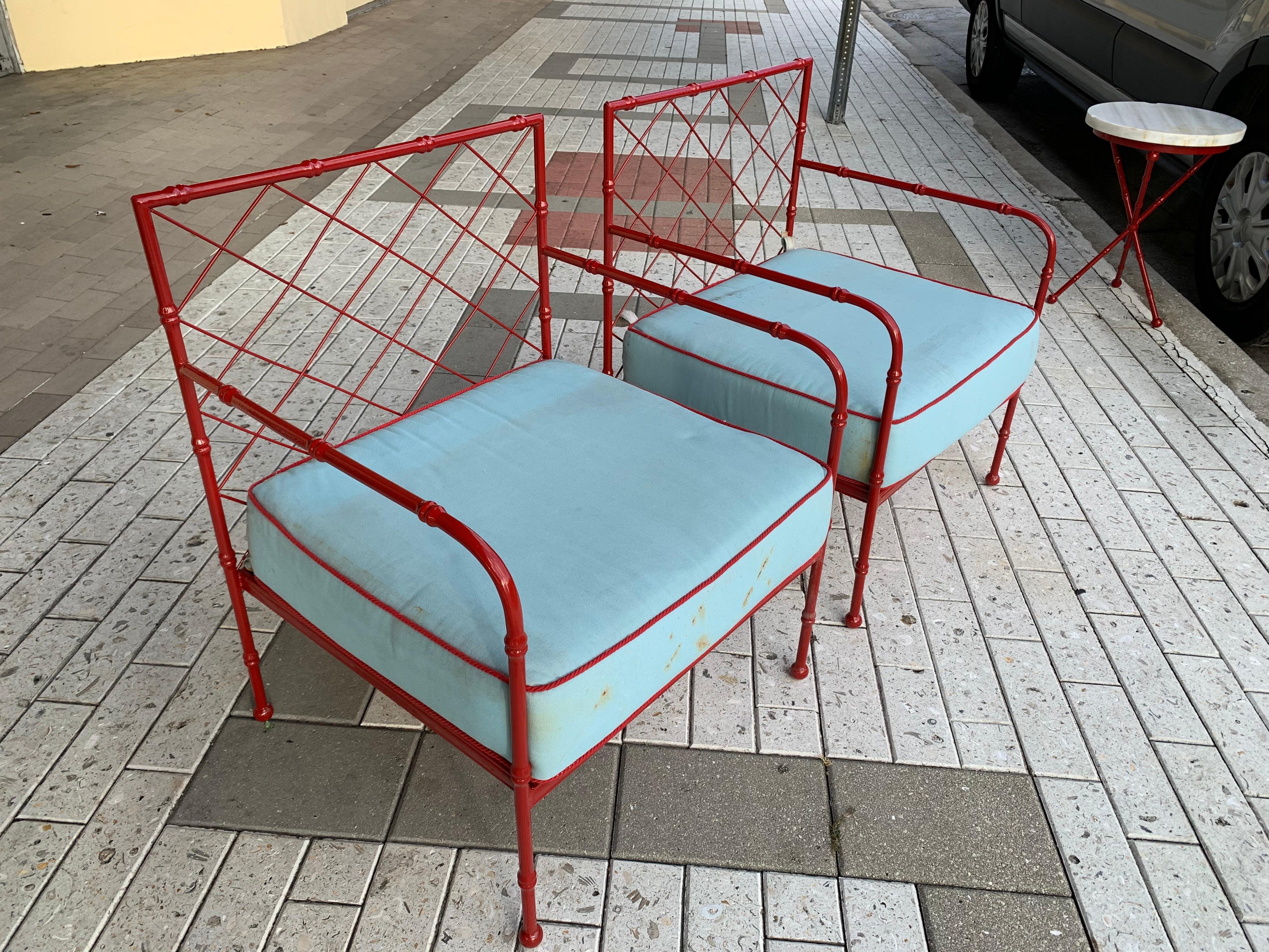 Deep red powder coating on this vintage pair of armchairs. faux bamboo design in heavy iron. This set in its original red has a few oxidization spotsm but very minor; cushion shown is vintage and has stains from use, we can have it reupholstered