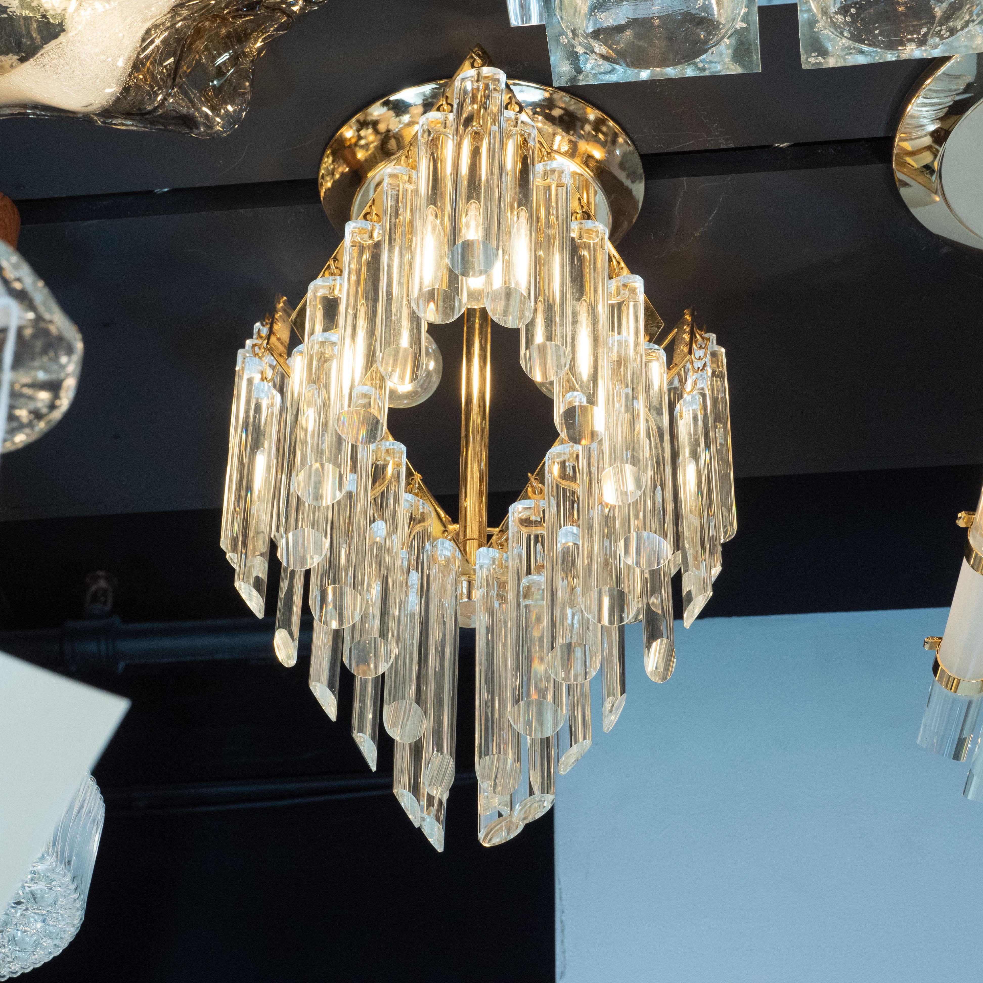 This stunning chandelier was realized by the venerable Austrian glassware company J. & L. Lobmeyr, circa 1970. The fixture hangs from a circular stepped base and consists of a central brass rod to which three upward-tilting, diamond-shaped brass