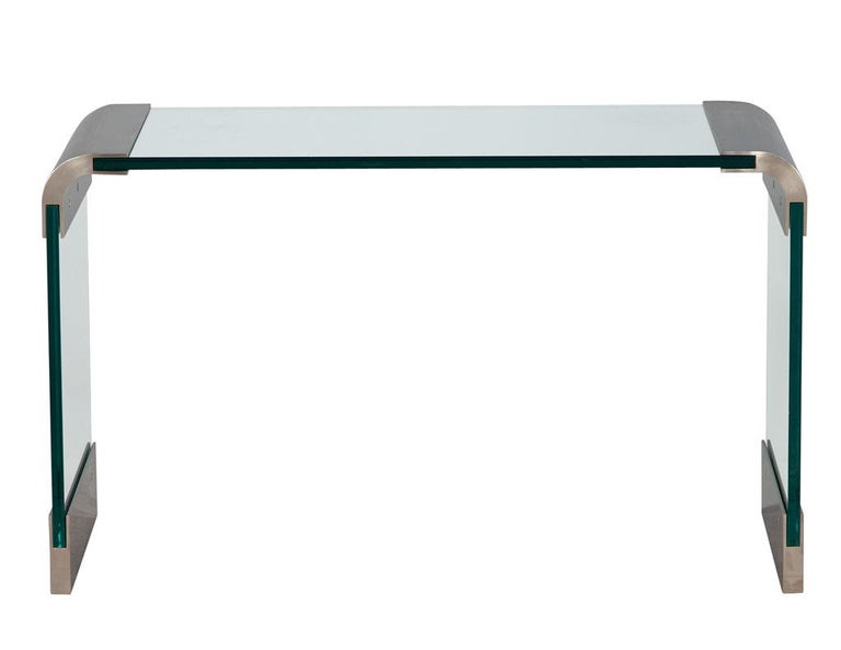 Mid-Century Modern curved glass and stainless-steel console table by PACE. America, circa 1970’s, by the Pace collection. Iconic mid-century design with curved stainless steel brackets creating a truly unique look. Thick glass panels complete the