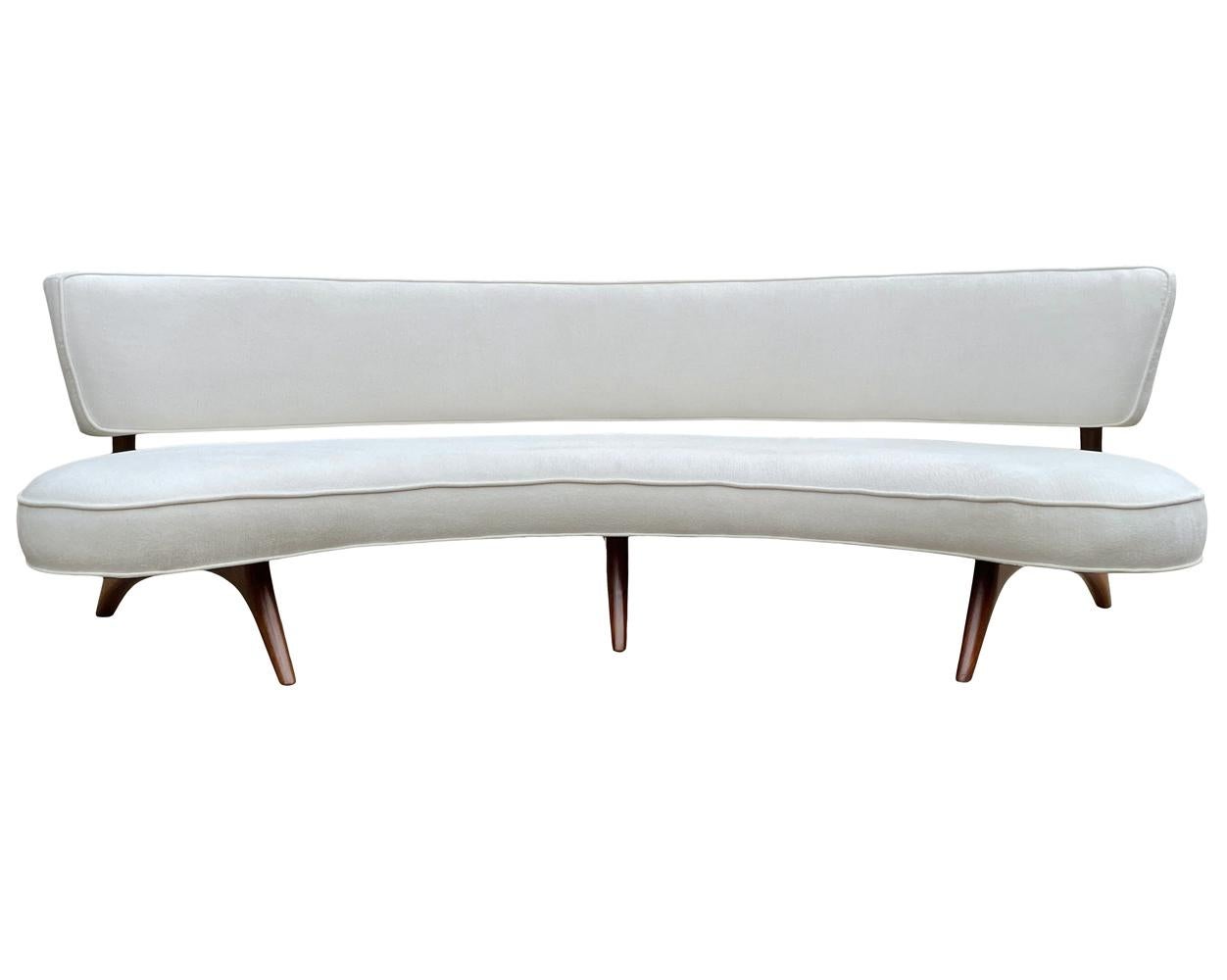 An early and fully restored curved sofa designed and produced by Vladimir Kagan circa 1950's. It consists of solid sculptural walnut legs and new white chenille fabric. Completely restored and ready for immediate use. Manufacturers label.