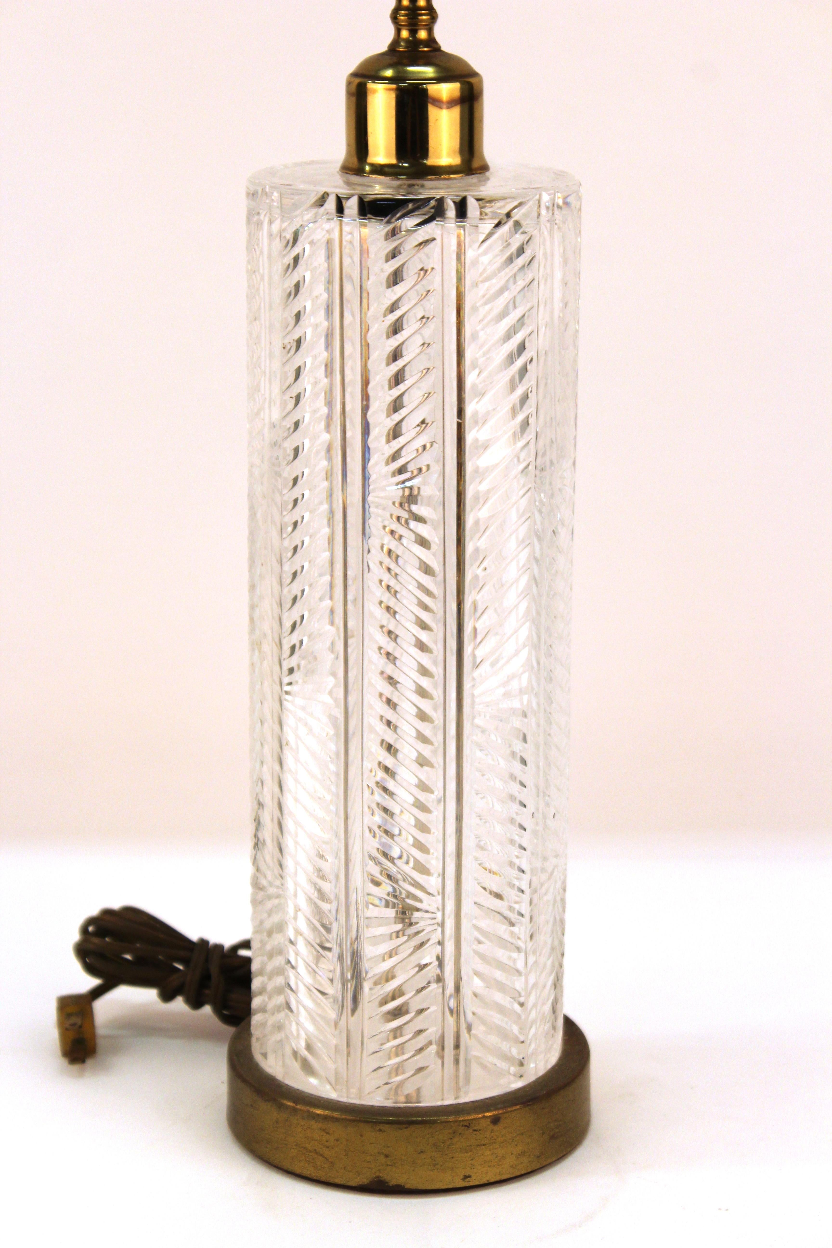 Mid-Century Modern cut crystal table lamp with a cylindrical shaped body in crystal atop a gilt circular base. The piece has a crystal finial and is in great vintage condition with minor age-related wear to the base.