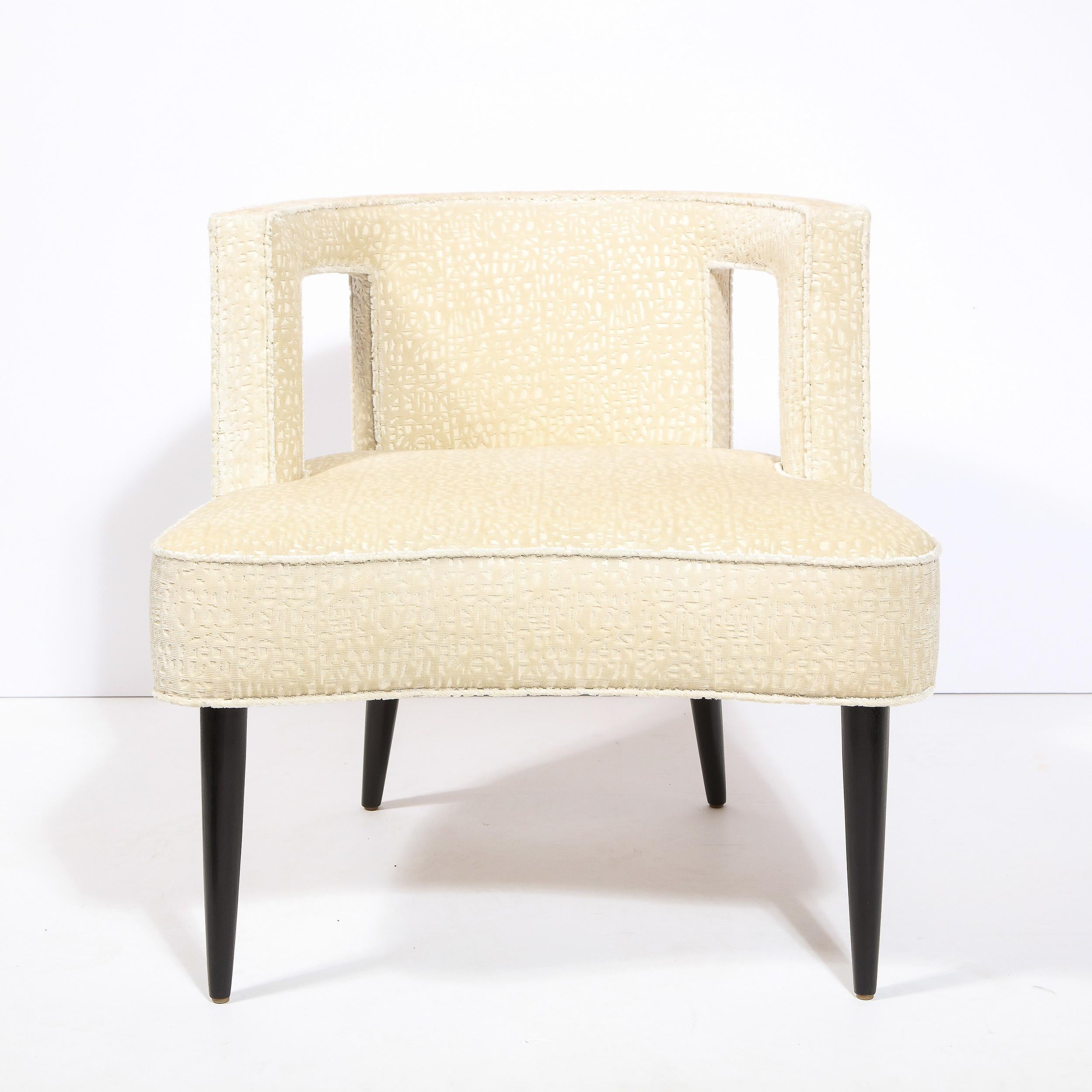 Dieser grafische und skulpturale Sessel wurde um 1950 in den Vereinigten Staaten hergestellt. Er hat eine tonnenförmige Rückenlehne mit zwei rechteckigen Formen, die aus der Rückenlehne herausgeschnitten sind, zylindrische, konische Füße aus
