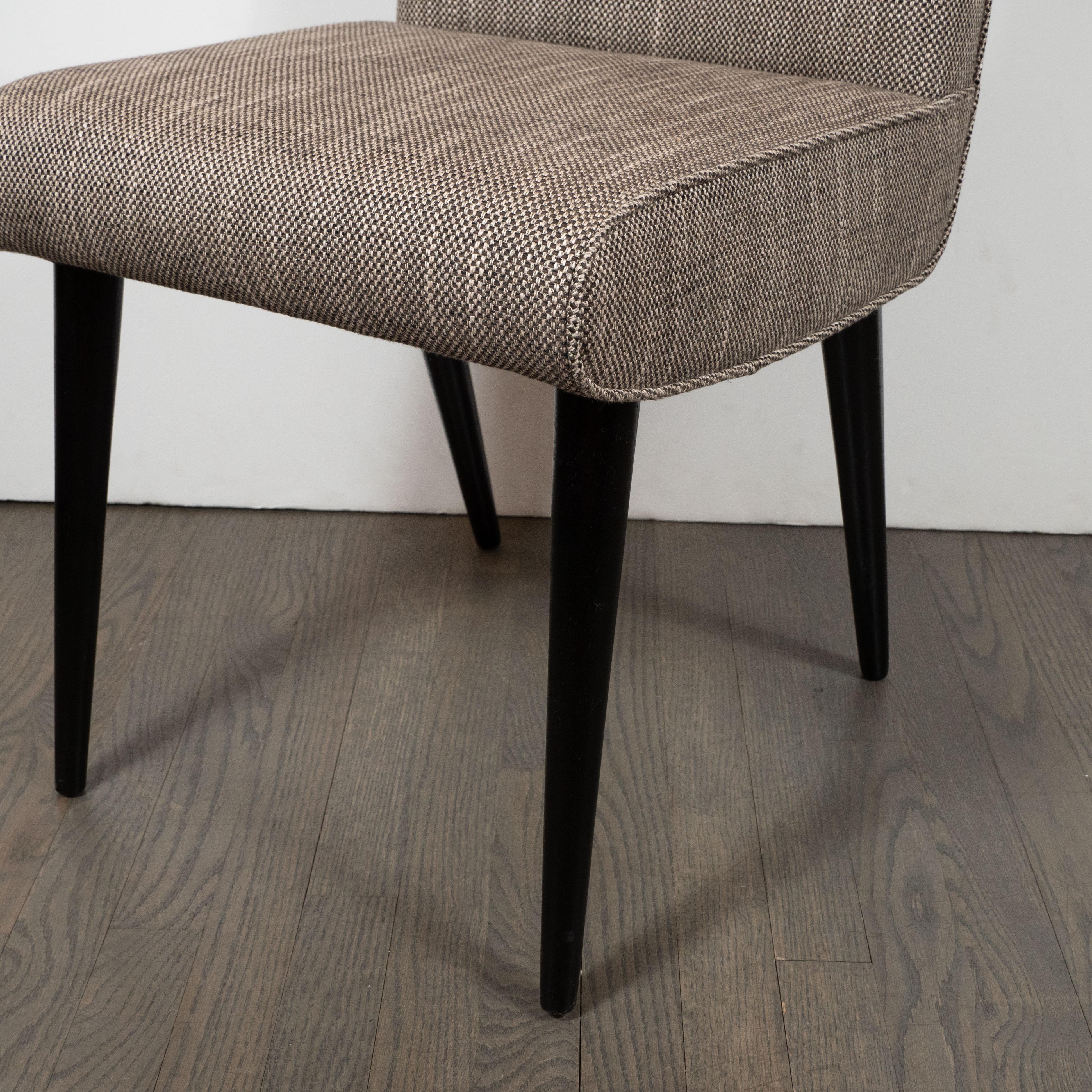 This elegant and refined Mid-Century Modern desk/side chair was realized in the United States, circa 1950. It features a rectilinear body with a square cutout in the center of the back sitting on four conical legs in ebonized walnut. The chair has