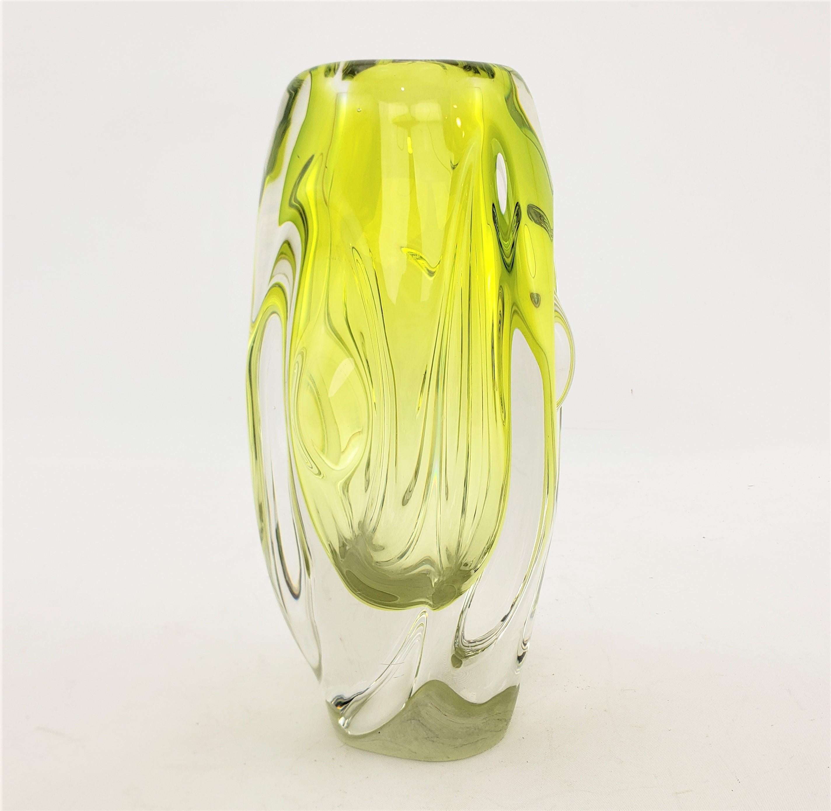 This art glass vase is unsigned, but presumed to originate from the Czech Republic and dating to approximately 1955 and done in the period Mid-Century Modern style. This vase is done with a thick clear glass with a submerged inner inclusion of