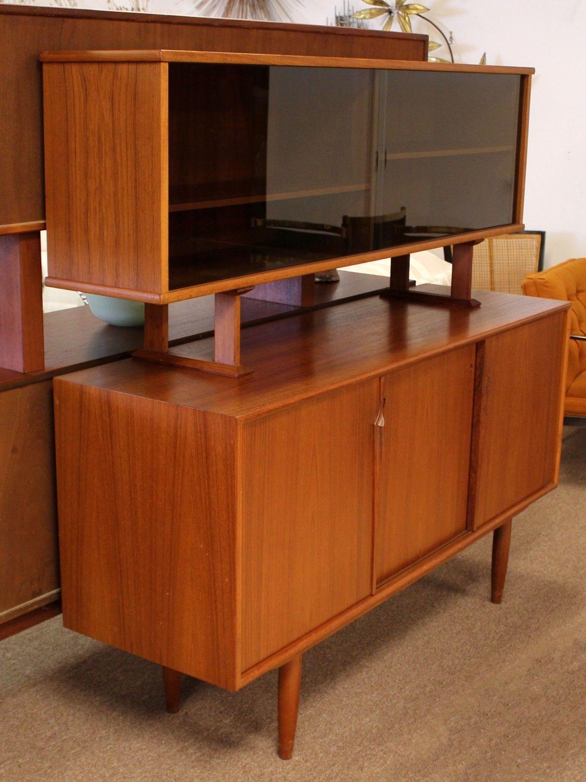 For your consideration is a marvelous, two-tiered sideboard, which features lower storage with a series of drawers and doors and a detachable upper shelving component with sliding glass doors, in the style of Kurt Ostervig. In excellent condition.
