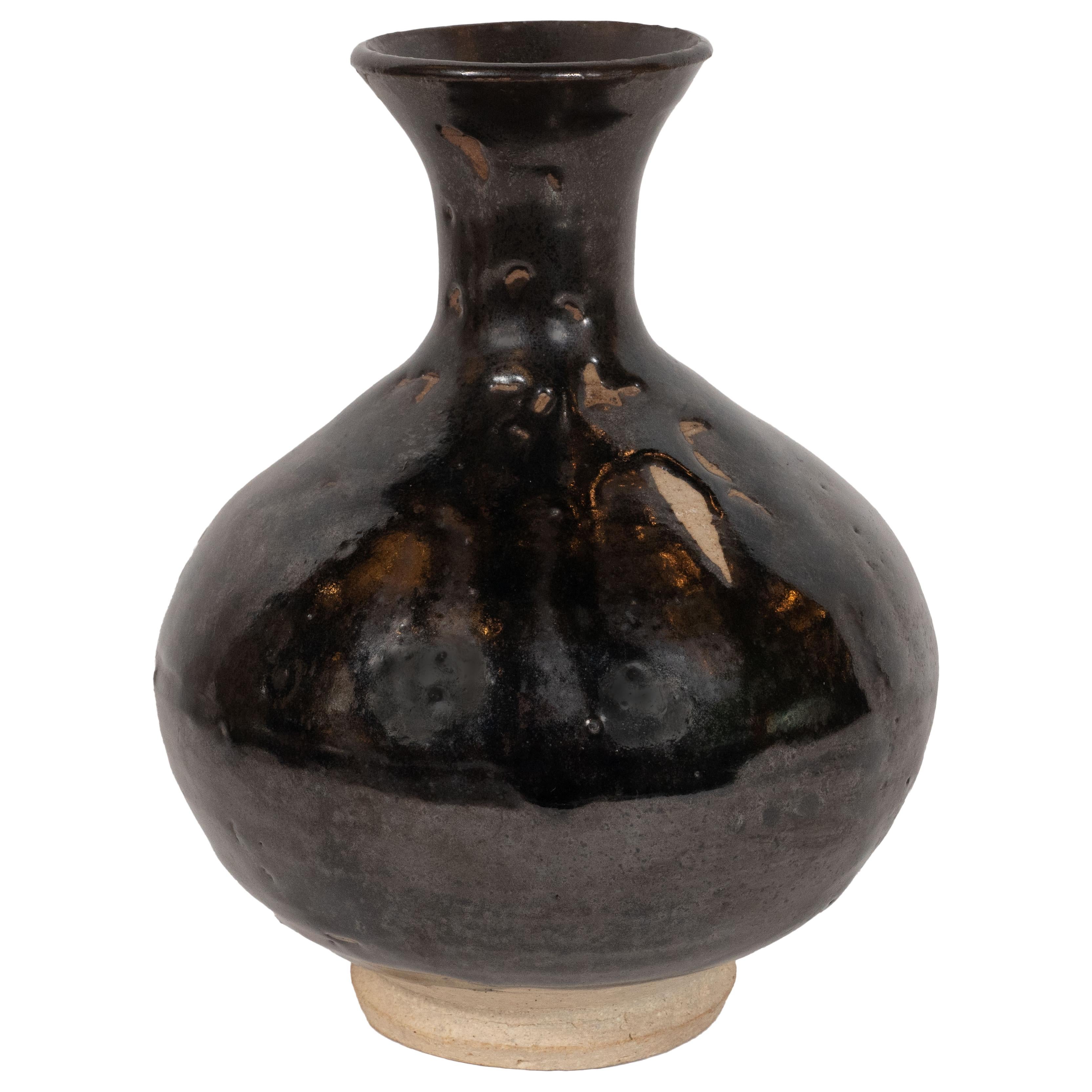 This refined Mid-Century Modern vase was realized in Denmark, circa 1960. It features a spherical body that dramatically tapers to its neck before again expanding outwards to its circular mouth. The exterior has been finished in a rich black lacquer