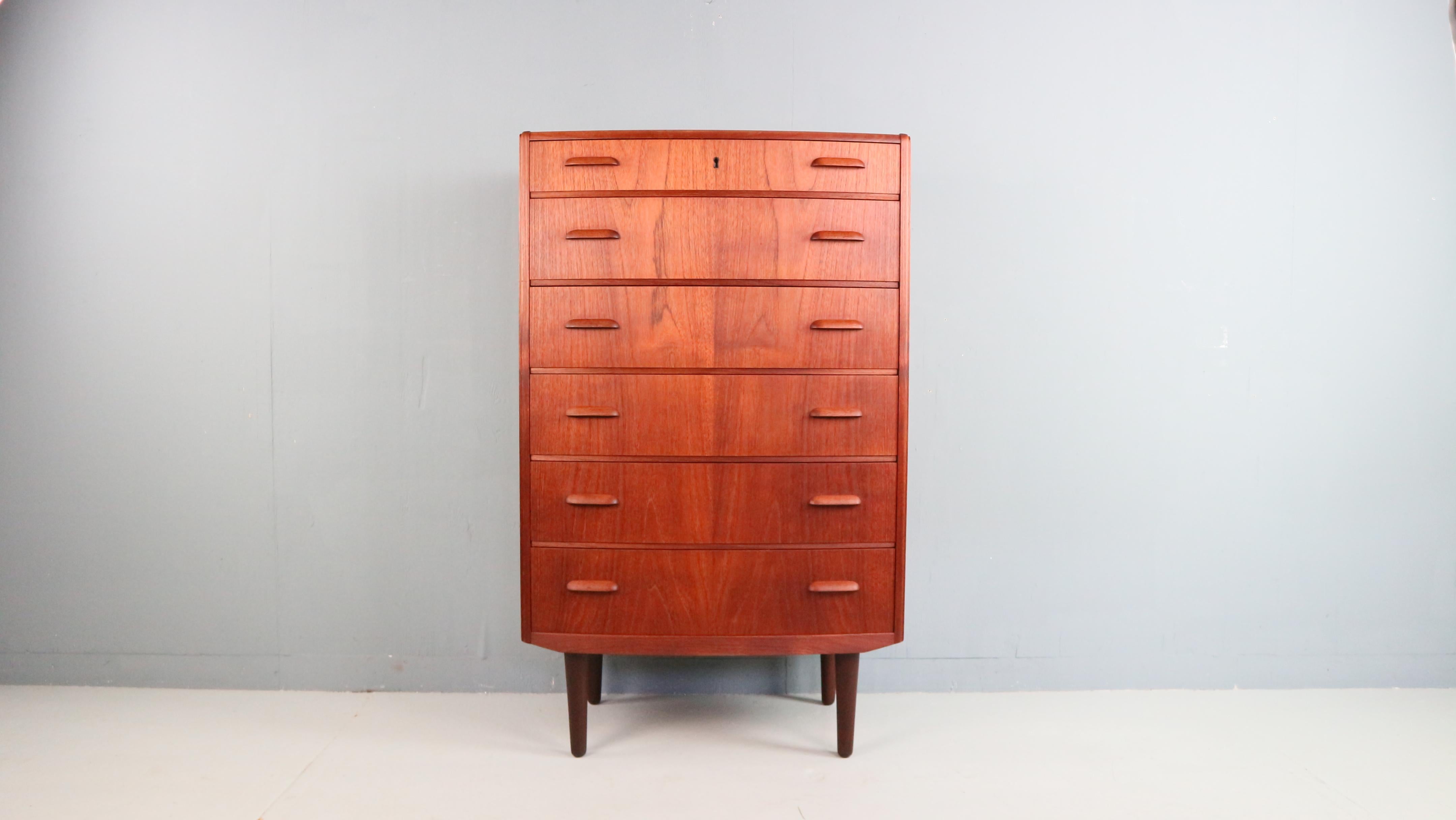 Elegante cómoda alta procedente de Dinamarca, diseñada en la década de 1960. Fabricado en cálida madera de teca y con seis espaciosos cajones. Las asas de madera sutilmente perfiladas añaden un carácter elegante y atemporal al diseño, un buen