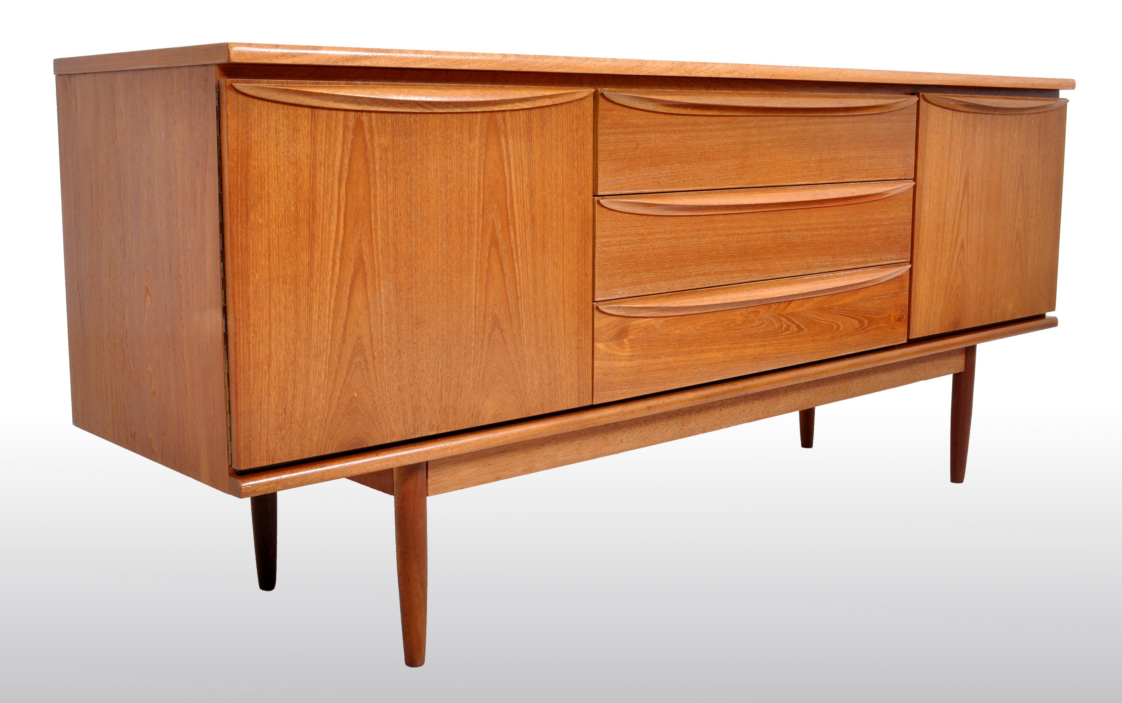 Mid-Century Modern Danish credenza in teak, 1960s. This very sleek credenza having a central bank of three drawers flanked to either side by cupboard doors enclosing single shelves. The credenza raised on gently tapering round legs.