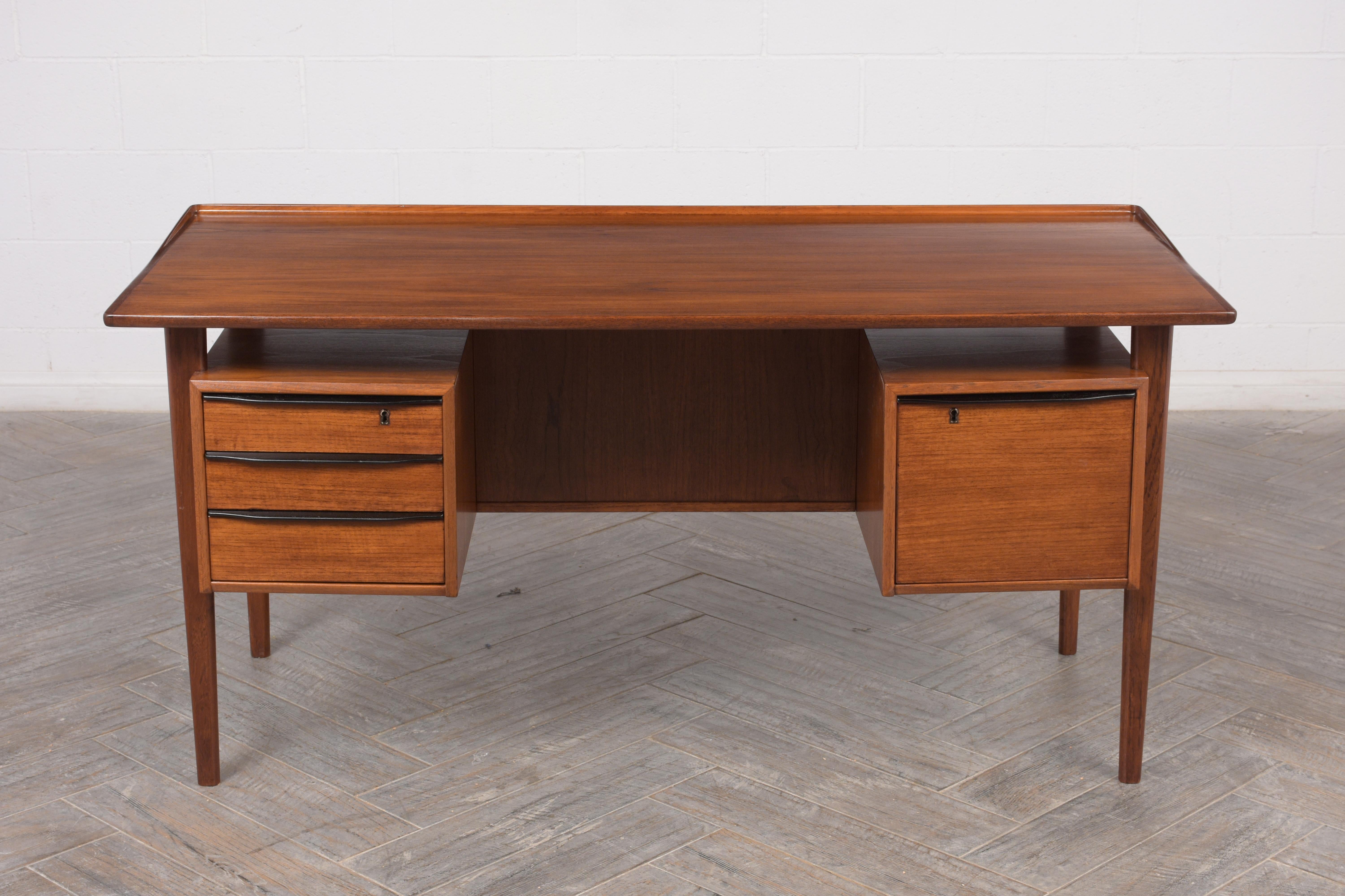 This 1960s Mid-Century Modern floating desk is made from teak wood stained a rich walnut and black color combination with a lacquered finish. The four drawers have carved wood handles finished in black color and the top drawers on each side with