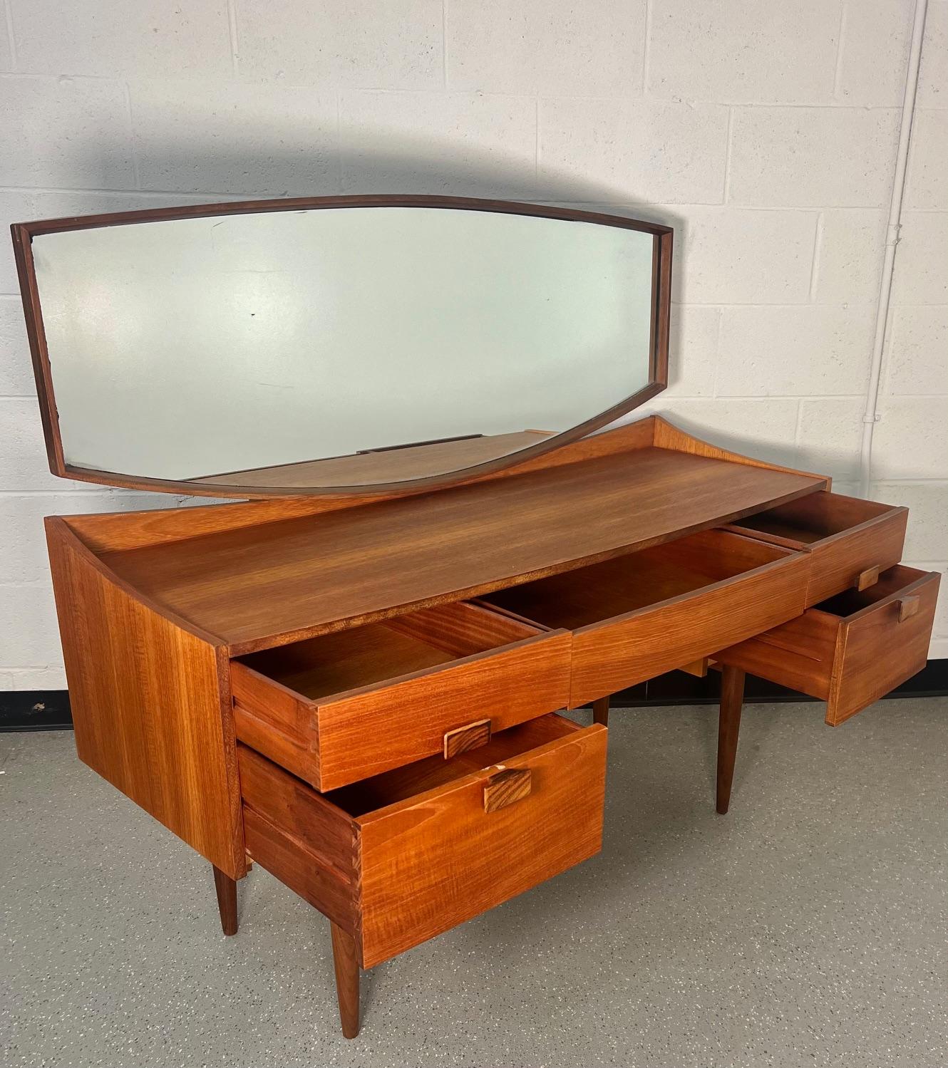 Fantastic midcentury teak veneer vanity with mirror. Designed by Danish designer Kofod-Larsen. Made by G Plan.

Features Kofod-Larsen's signature split handle design on the drawers. The handles are stained rosewood.
Very good vintage condition. All