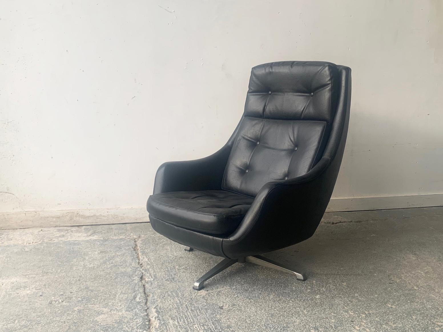 A 1970’s mid century high backed swivel lounge chair. Made by ‘ Kanari’ in the 1970’s. 3 separate cushions upholstered in the original black leatherette with button detailing.  Sits on 4 pronged steel splayed base with rubber tips. 

2 identical