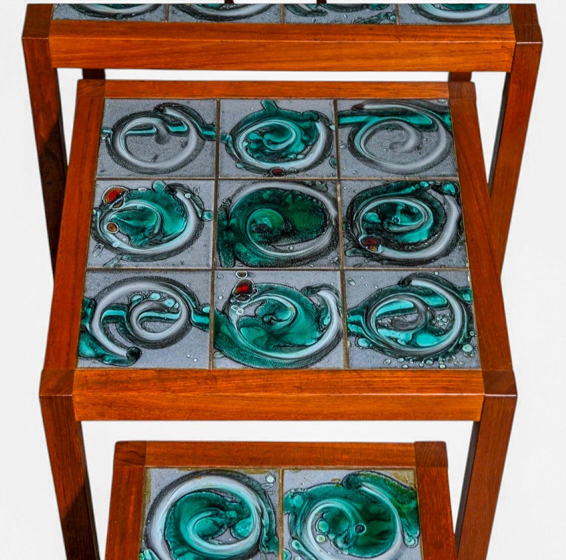J'adore ce set. Il s'agit d'un ensemble de tables gigognes danoises modernes des années 1960 avec de magnifiques carreaux de faïence travaillés à la main. Les carreaux sont un mélange de gris, de roux et de verts. Les cadres en teck sont en très bon