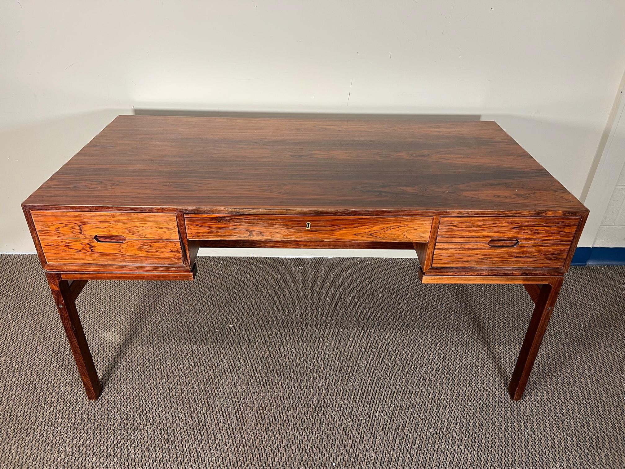 Fantastic midcentury rosewood desk. Designed by Arne Wahl Iversen. Free standing with bookcase at the back.
Fantastic condition overall. Some fading and loss of finish. Scratches on the top. Veneer chip at the back left corner.

Dimensions: