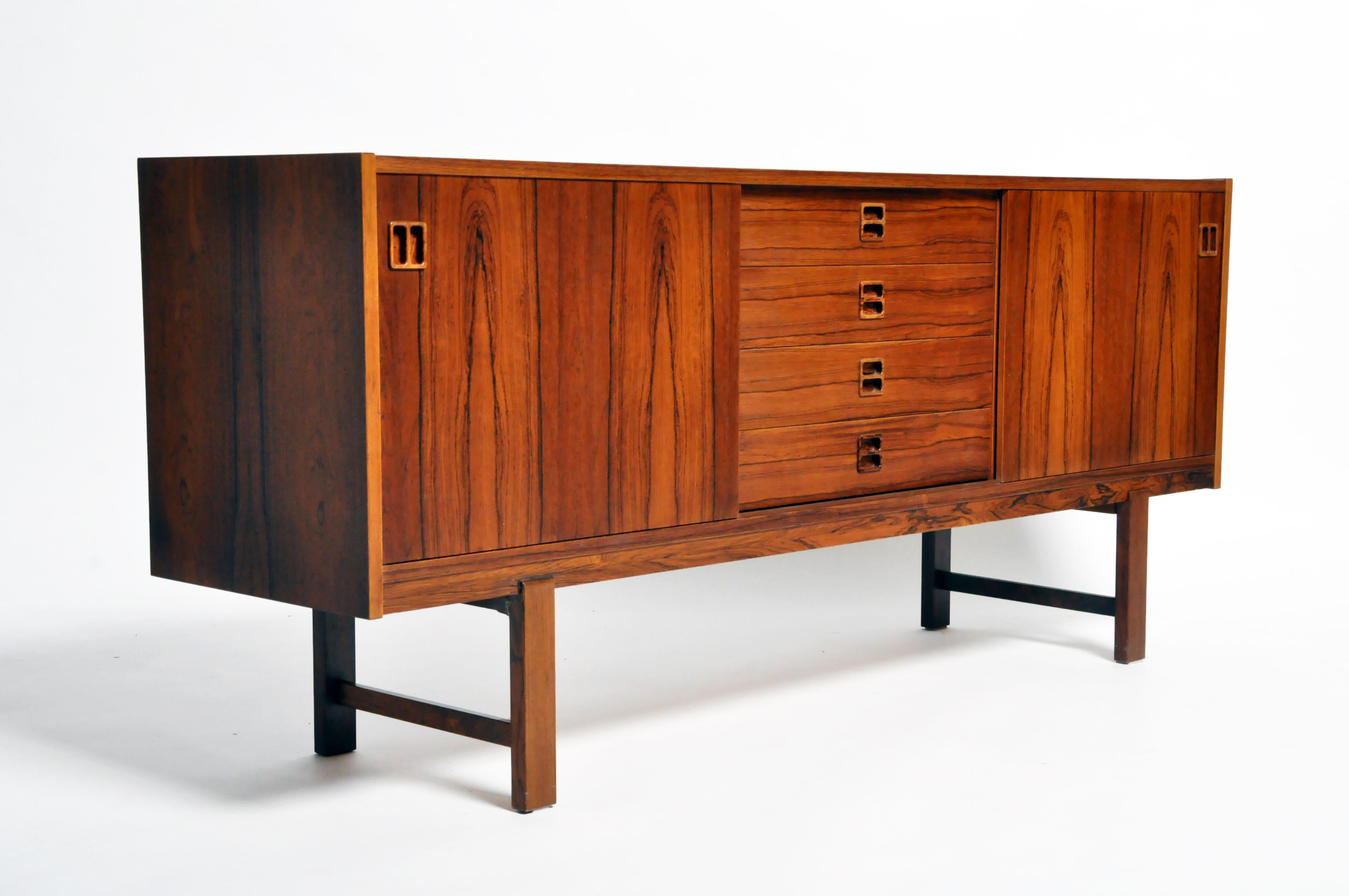 This handsome Mid-Century Modern sideboard is from Denmark and made from walnut veneer, circa 1960. The piece features 4 drawers and 2 sliding doors that open up to shelves for additional storage.