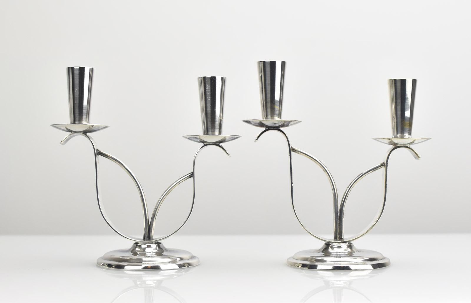 Este elegante par de candelabros dobles escandinavos de la Modernidad de Mediados de Siglo están fabricados en latón plateado por el prestigioso fabricante danés Berg, y datan de los años 50-60. 

Cada pieza presenta unos brazos grácilmente
