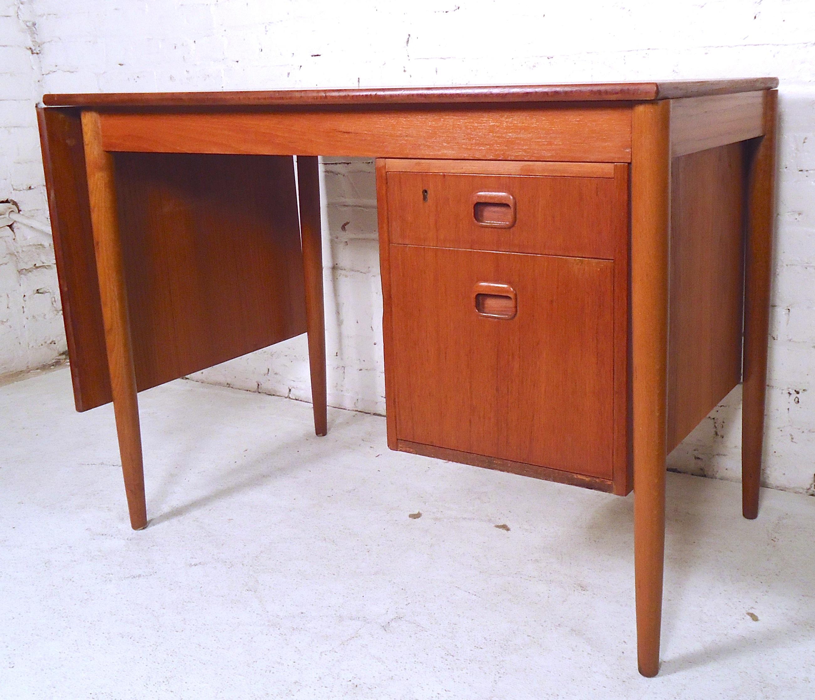 Stunning vintage modern desk features the unique ability to extend the width of the top by sliding it to the side. Beautiful teak wood grain, long tapered legs, and a finished back show quality craftsmanship. 

Please confirm item location (NY or