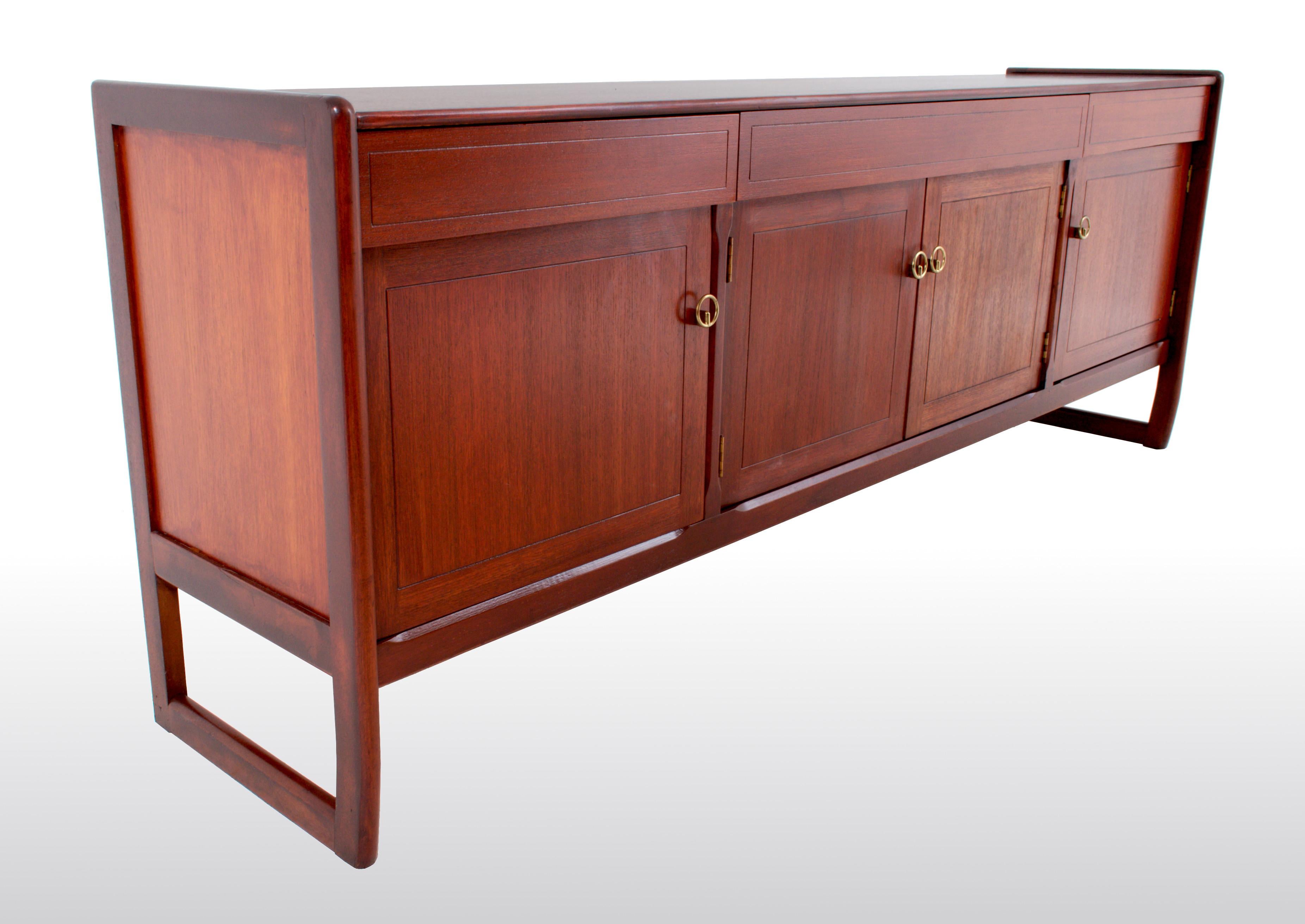 Mid-Century Modern Danish style credenza in walnut, 1960s. This sleek credenza having three drawers to the top, four cupboard doors below, each enclosing a single shelf. The credenza raised on continuous legs.