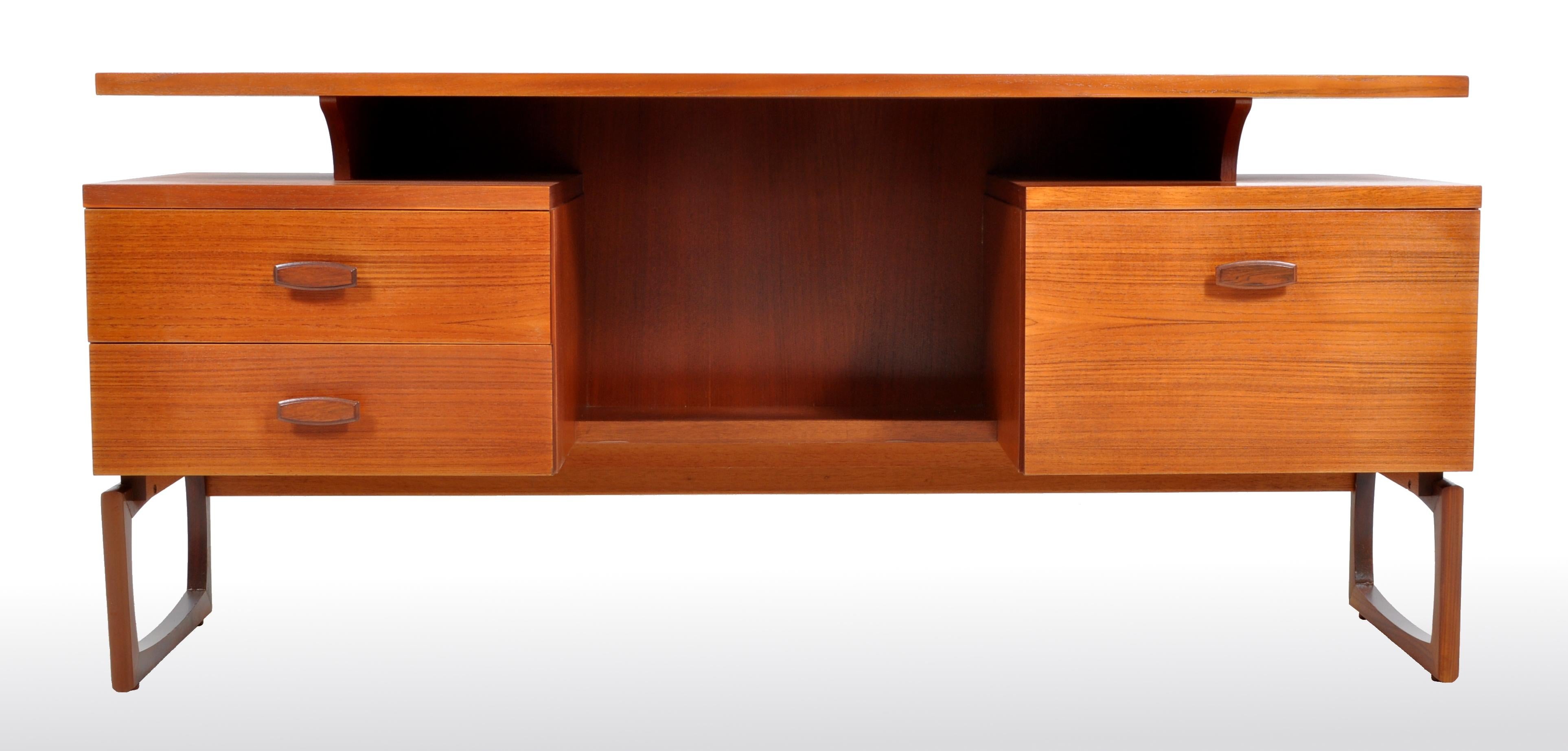 Mid-Century Modern Danish style teak floating top desk by Ib Kofod-Larsen for G Plan, 1960s. The desk having a curvilinear floating top writing surface above twin pedestals, to the left a bank of two drawers and to the right a single cupboard. The
