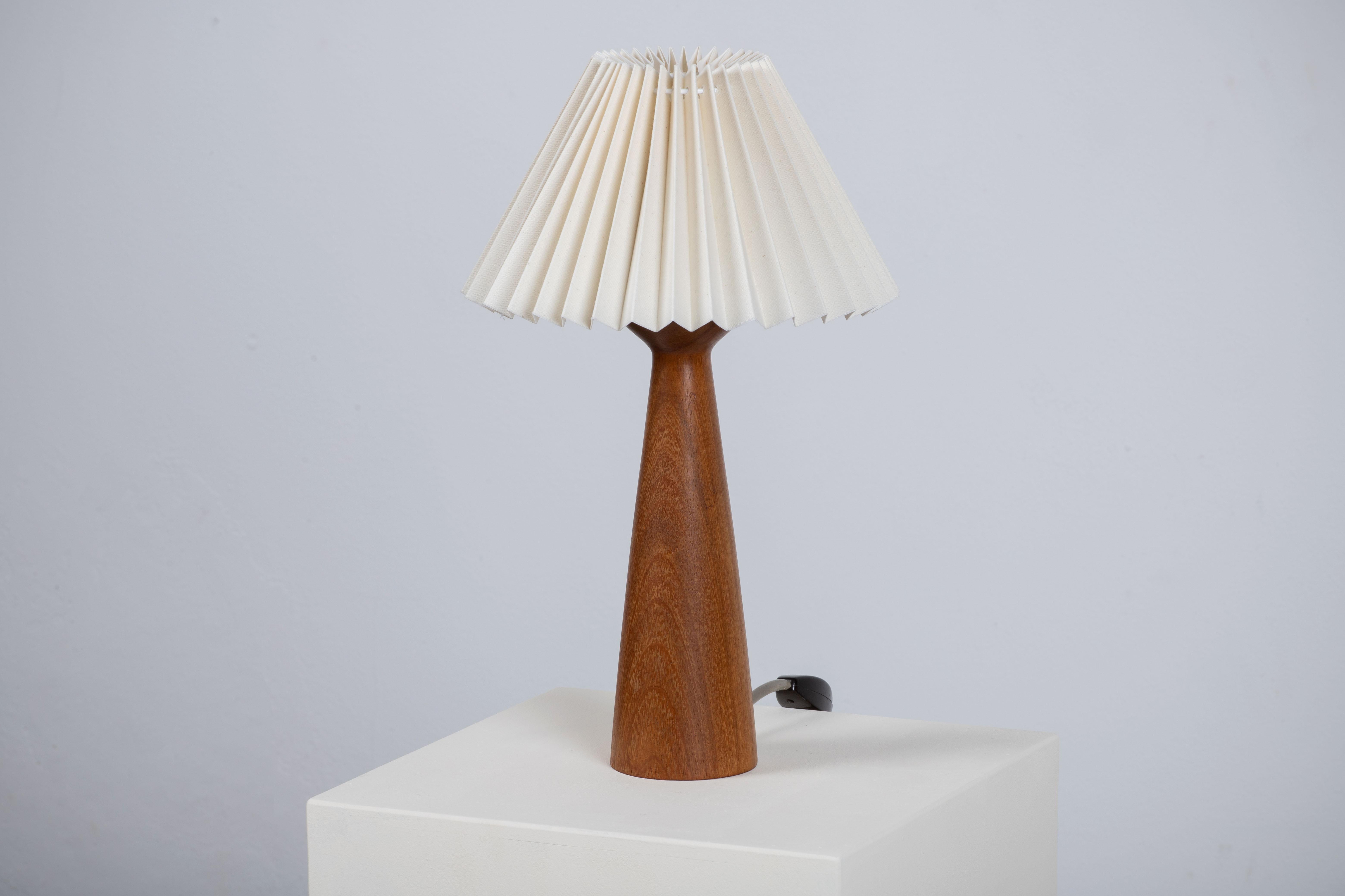 A mid-century table lamp. In solid teak, Denmark, 1960. 

Elegant teak lamps, pleated lampshade. It is in good general condition and works perfectly. The diffused light is very pleasant and the lamp offers a warm atmosphere.

Height without