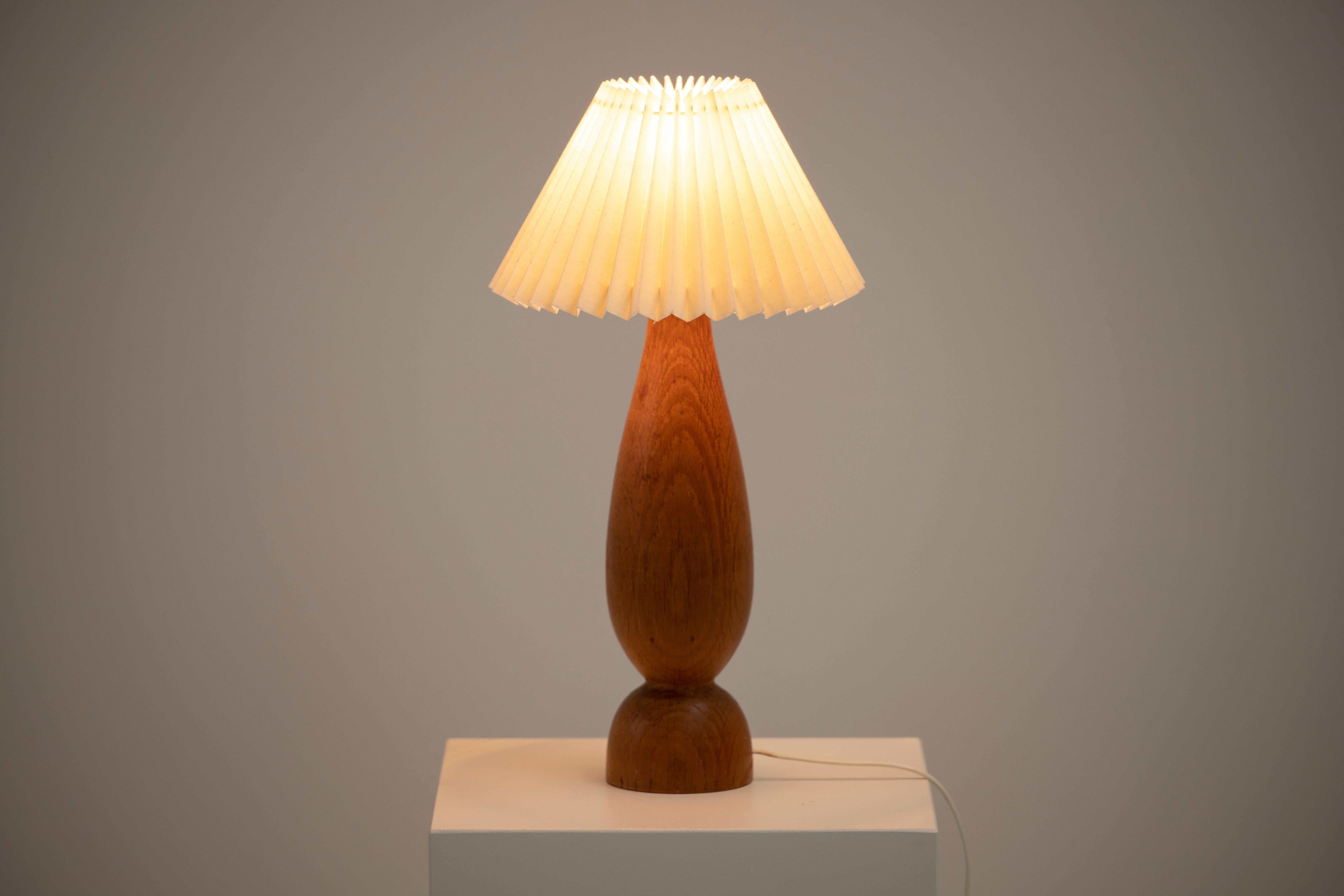 A mid-century table lamp. In solid teak, Denmark, 1960. 

Elegant teak lamps, pleated lampshade. It is in good general condition and works perfectly. The diffused light is very pleasant and the lamp offers a warm atmosphere.

Sold without