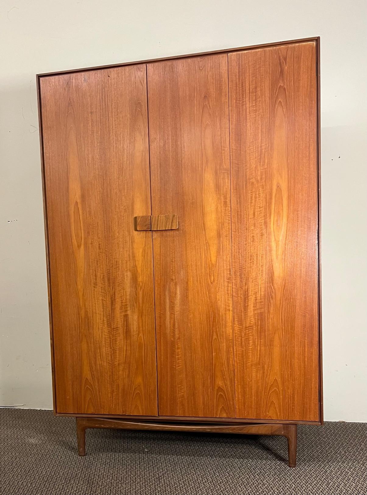 Amazing 3 door armoire by renowned Danish designer Kofod Larsen for G Plan's Danish range.
Teak with Larsen's signature rosewood handles. Signed on the left door.

Nice vintage condition. Some fading on the doors. Some small chips and marks from