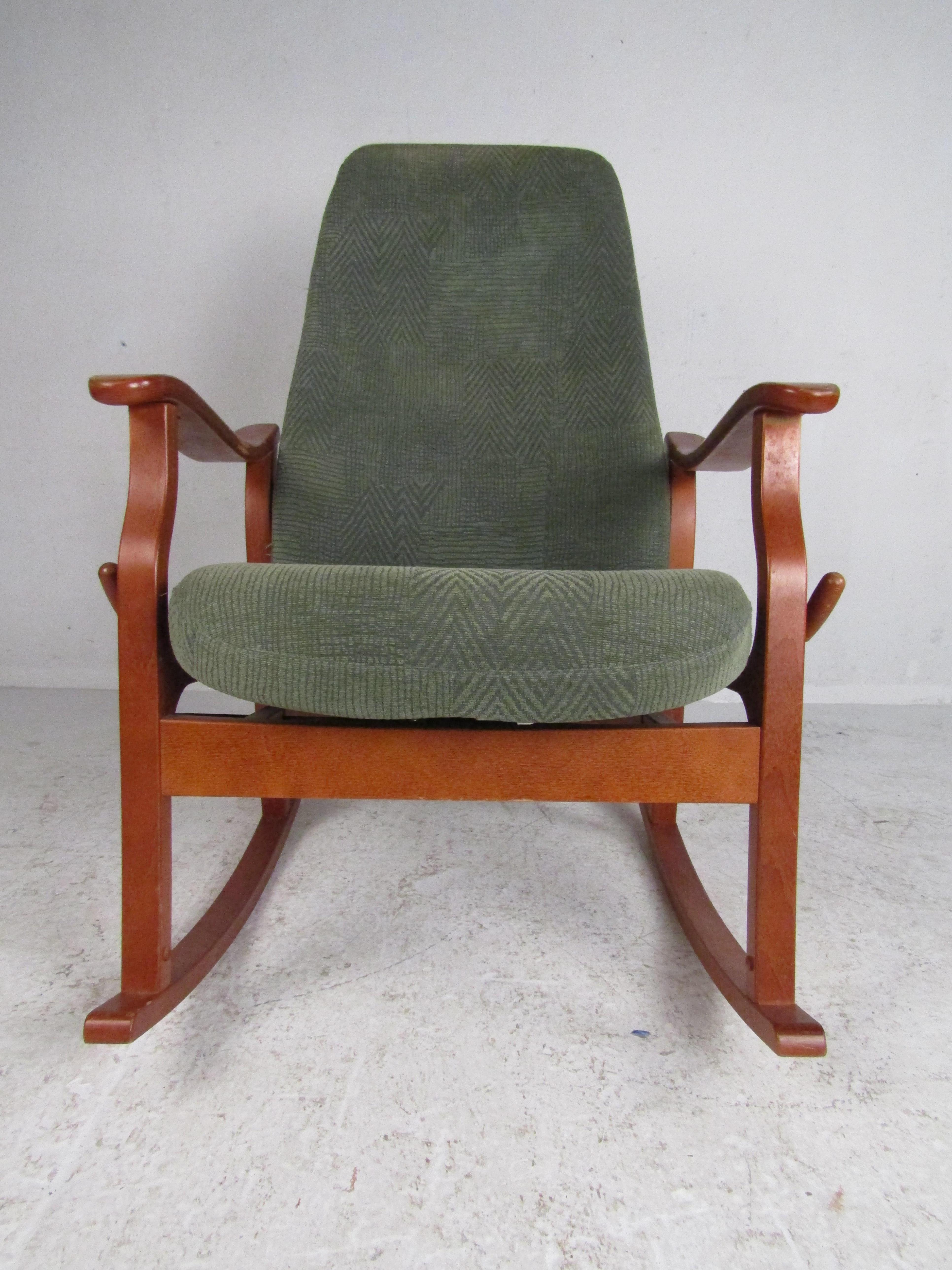 This stunning vintage modern rocking chair features a sculpted teak frame, overstuffed seats covered in green upholstery, and an adjustable lever on the right side. This impressive vintage modern rocker makes the perfect addition to any seating