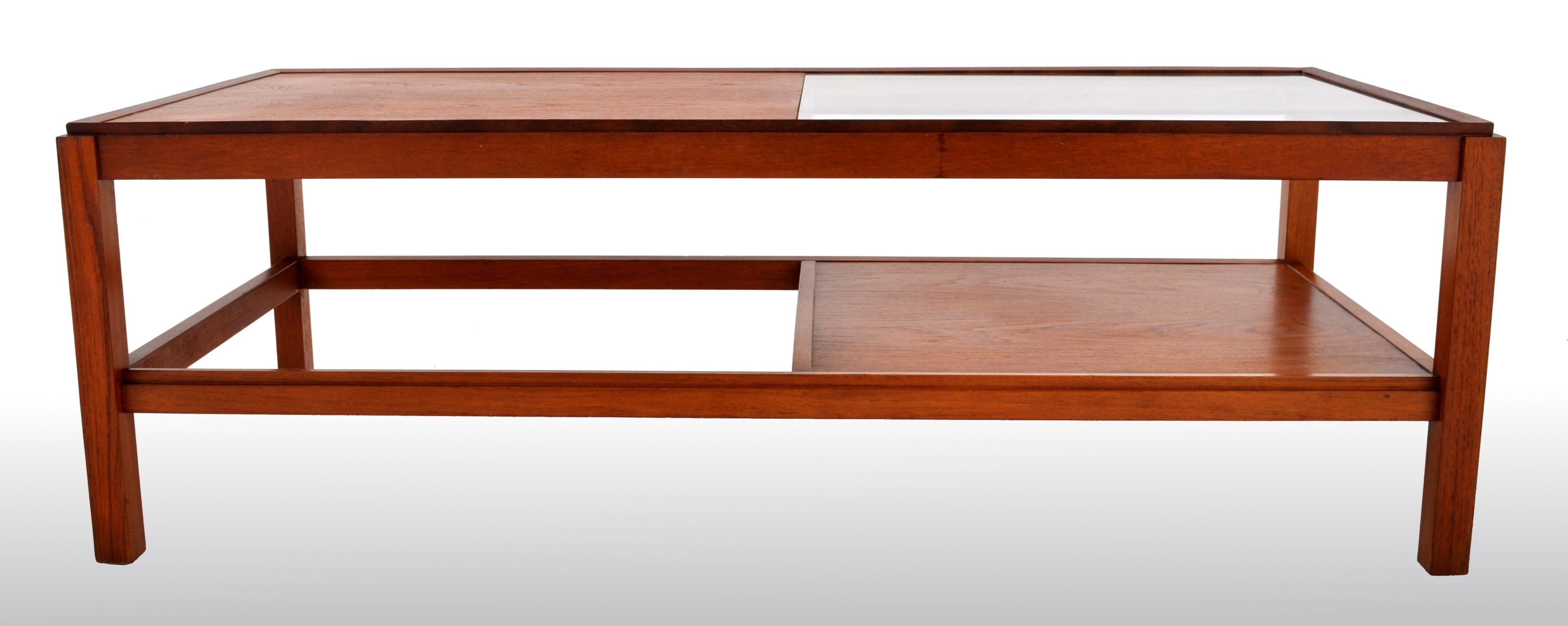 Mid-Century Modern Danish teak coffee table, 1960s. The twin-tiered table of large form having a glass inset to the top and having a secondary tier underneath. The table made of solid figured teak and raised on square legs.