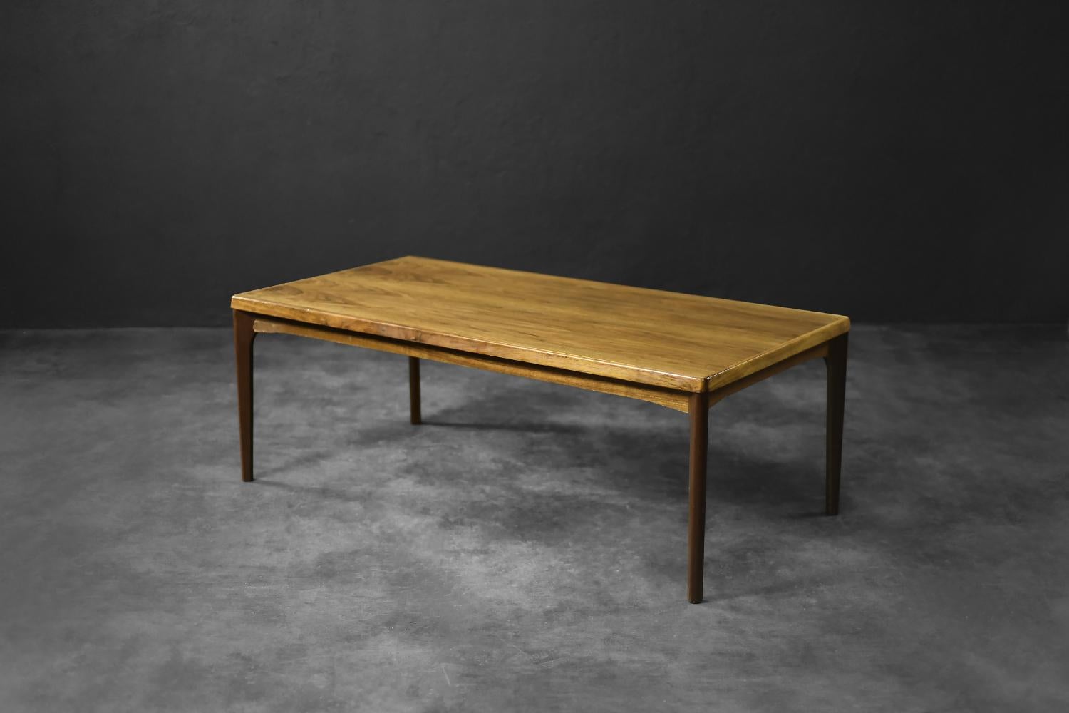 Cette table basse minimaliste a été conçue par Henning Kjærnulf pour le fabricant danois Vejle Møbelfabrik A/B dans les années 1960. Il est fabriqué en teck de haute qualité dans une teinte brune chaude et profonde. Il allie une forme minimaliste à