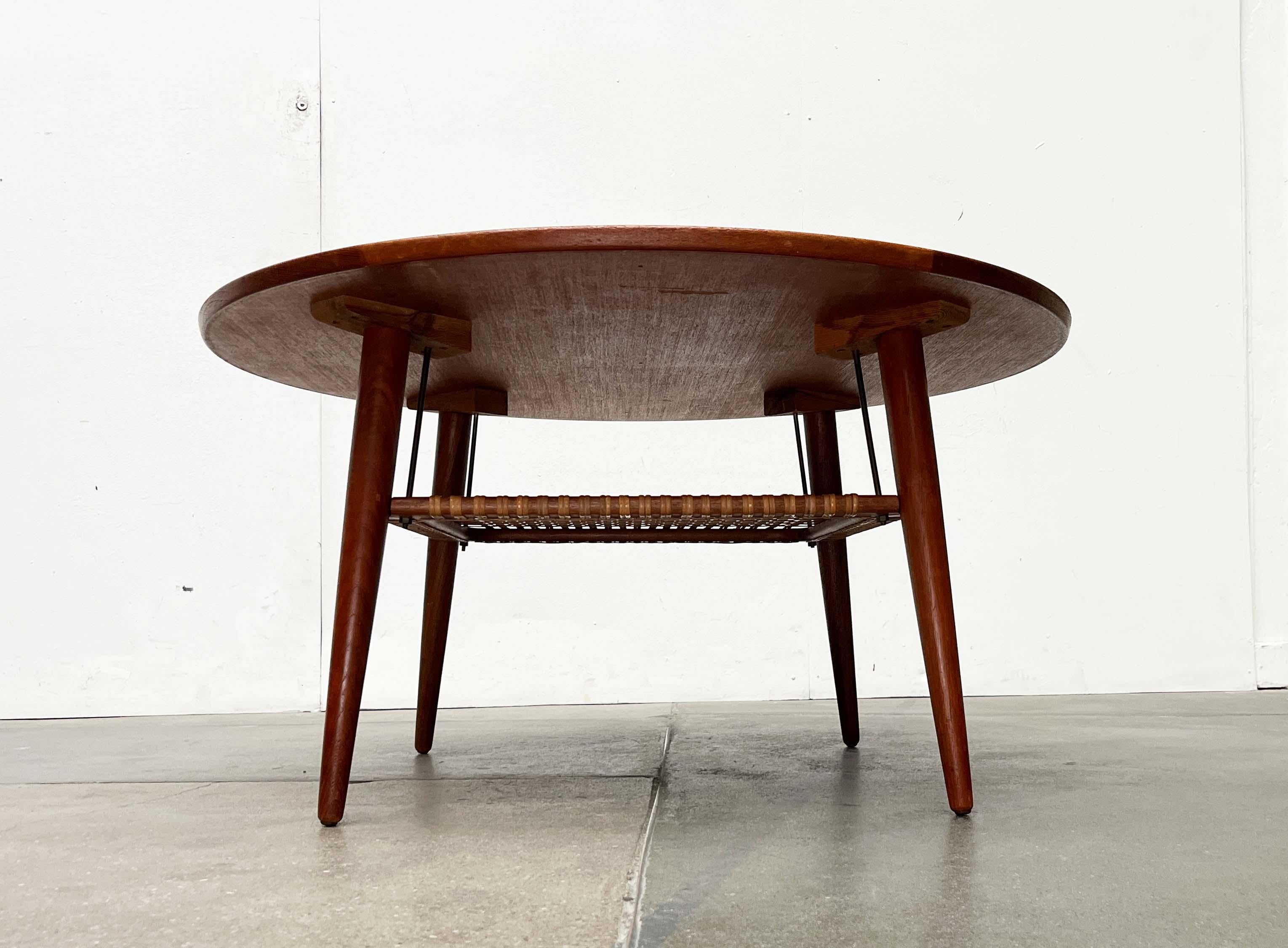 Tavolino rotondo in teak proveniente dalla Danimarca con ripiano portaoggetti intrecciato.

Un design elegante con una patina meravigliosa. Il piano del tavolo impiallacciato è incorniciato da un ampio bordo in legno massiccio. Le quattro gambe sono