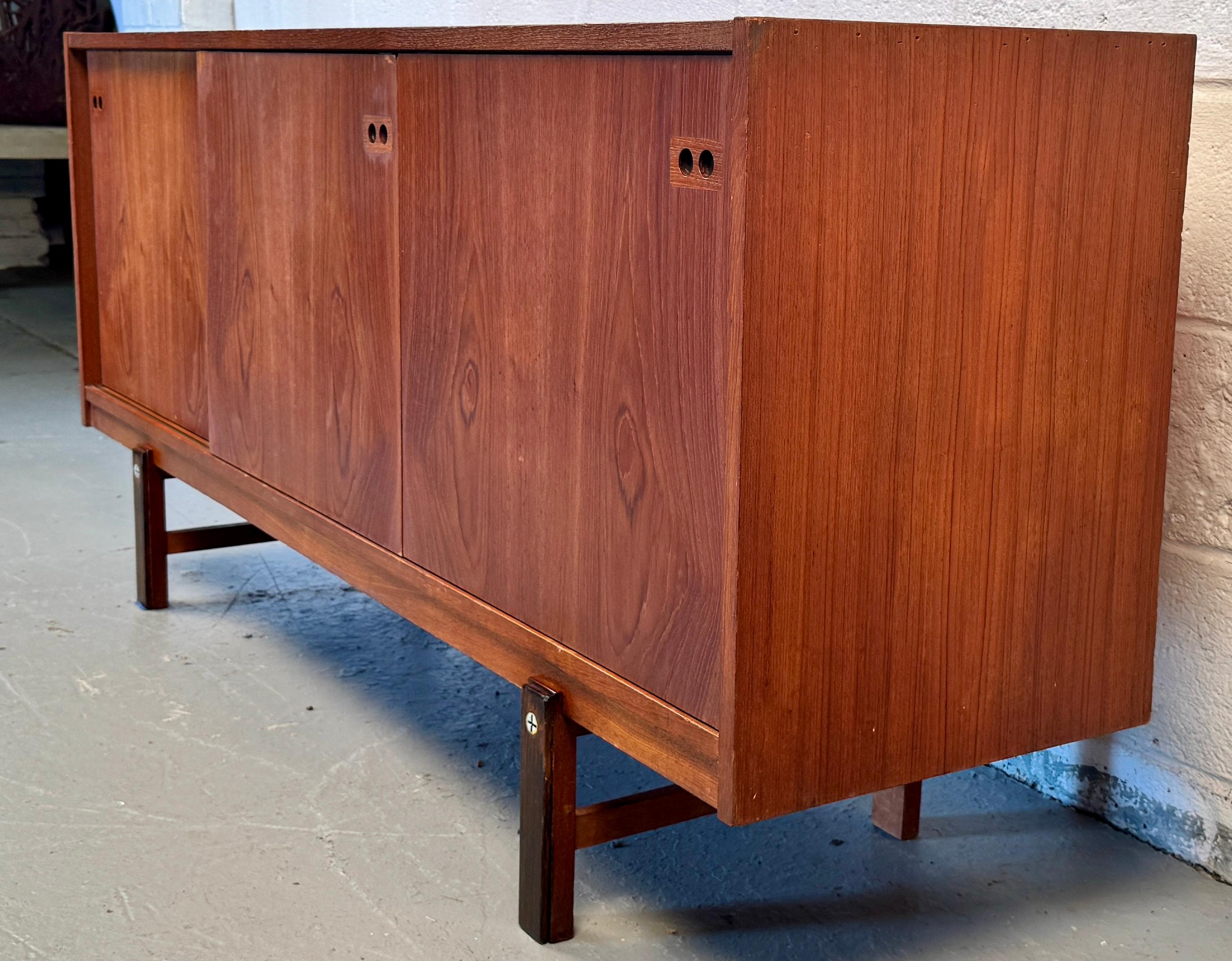 Embodying the essence of mid-century Scandinavian elegance, this Danish Modern Teak Credenza is a stunning example of minimalist form meeting functional beauty. Likely designed by renowned Danish designer Ib Kofod-Larsen, this piece showcases the