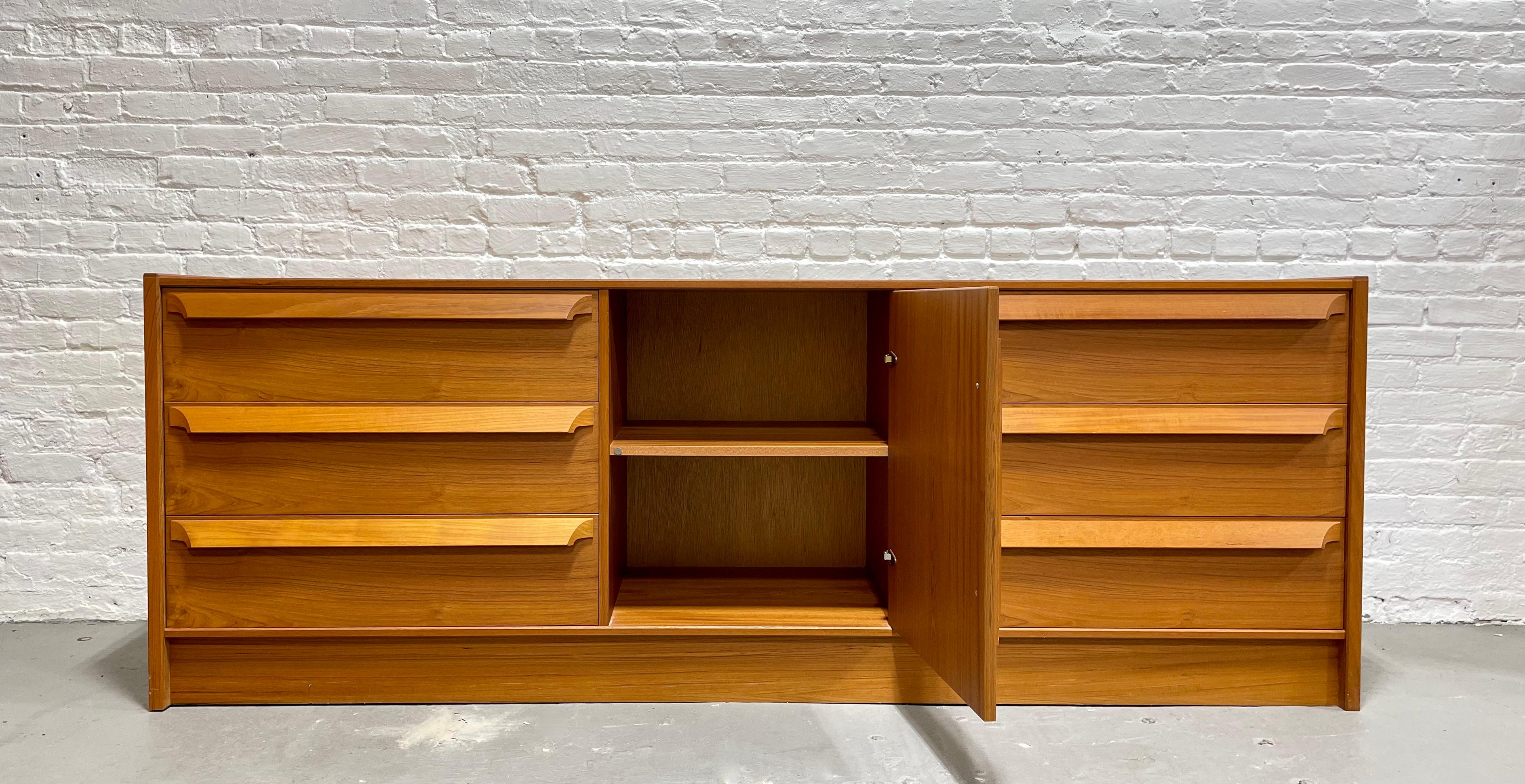 Sculpted Mid-Century Modern danish teak credenza / long dresser by Skovby Mobelfabrik. This gorgeous credenza features loads of storage space in a thoughtful combination of drawers and shelving space. Constructed in teak with lovely wood grains and
