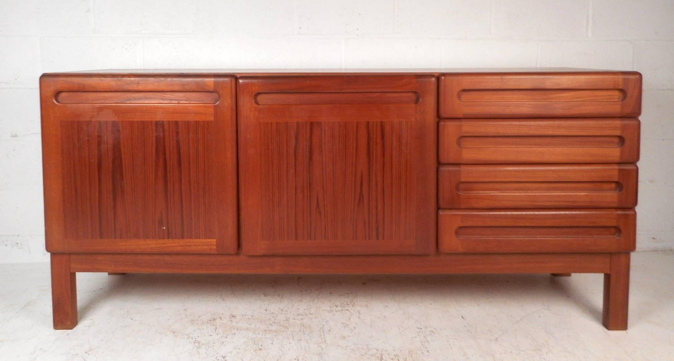 This beautiful vintage modern Danish sideboard features plenty of room for storage within its two hidden compartments with shelves and four large drawers. This unique midcentury case piece shows quality construction with recessed oblong shaped
